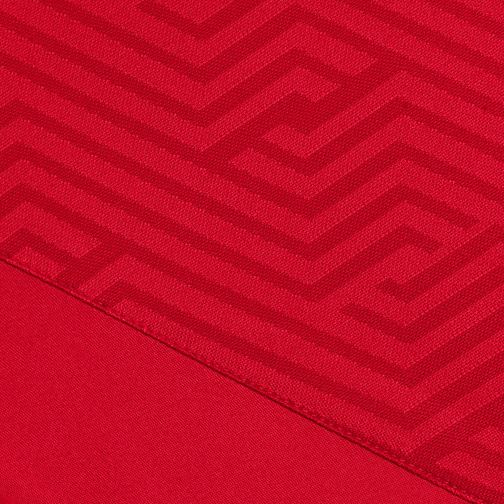 Nærbilde av rød Player shirt S/S Monaco v24, Match & Training wear, med geometrisk zigzag-stoffstruktur.