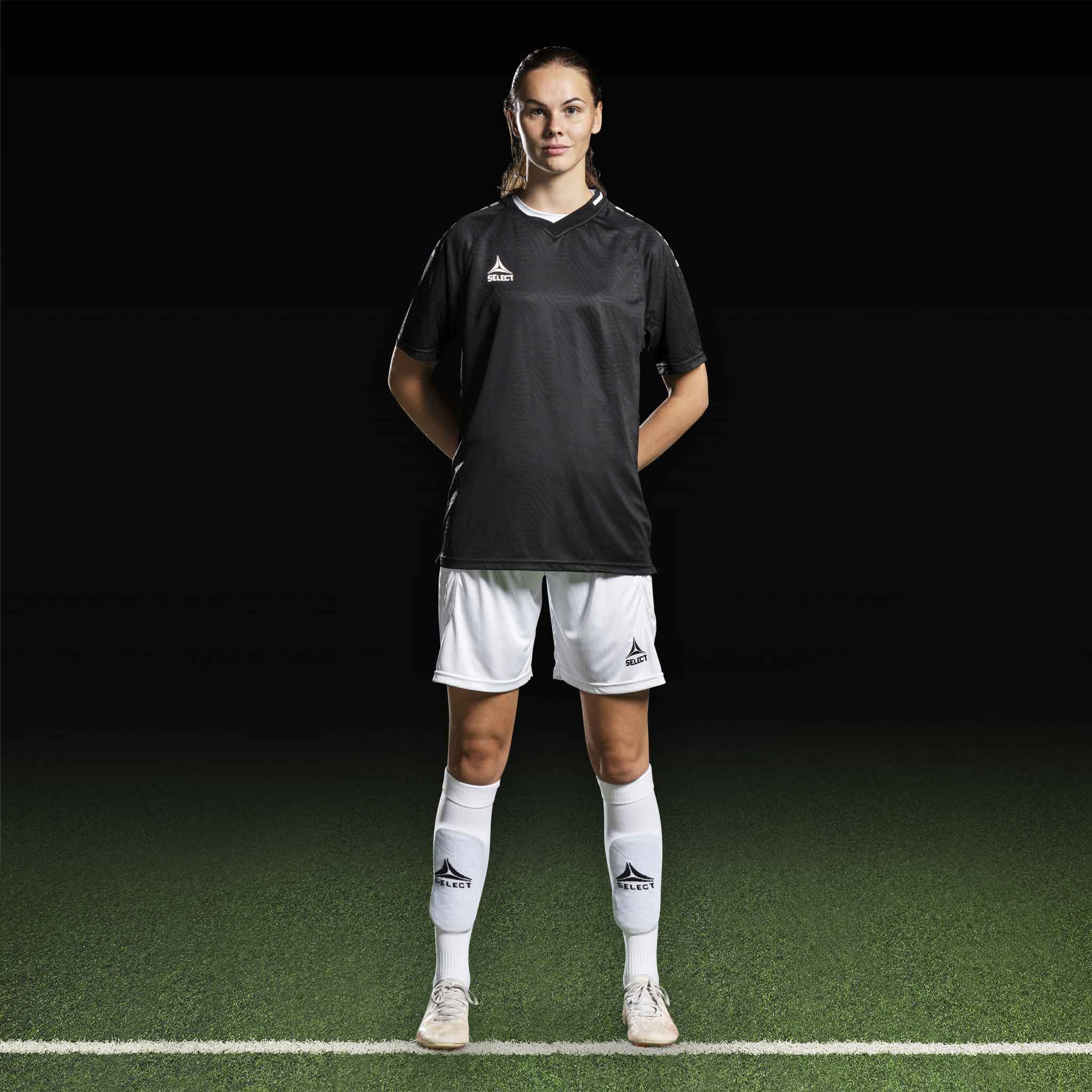 Kvinnelig fotballspiller i sort Player shirt S/S Monaco v24, hvite shorts og strømper. Kamp- og treningstøy.
