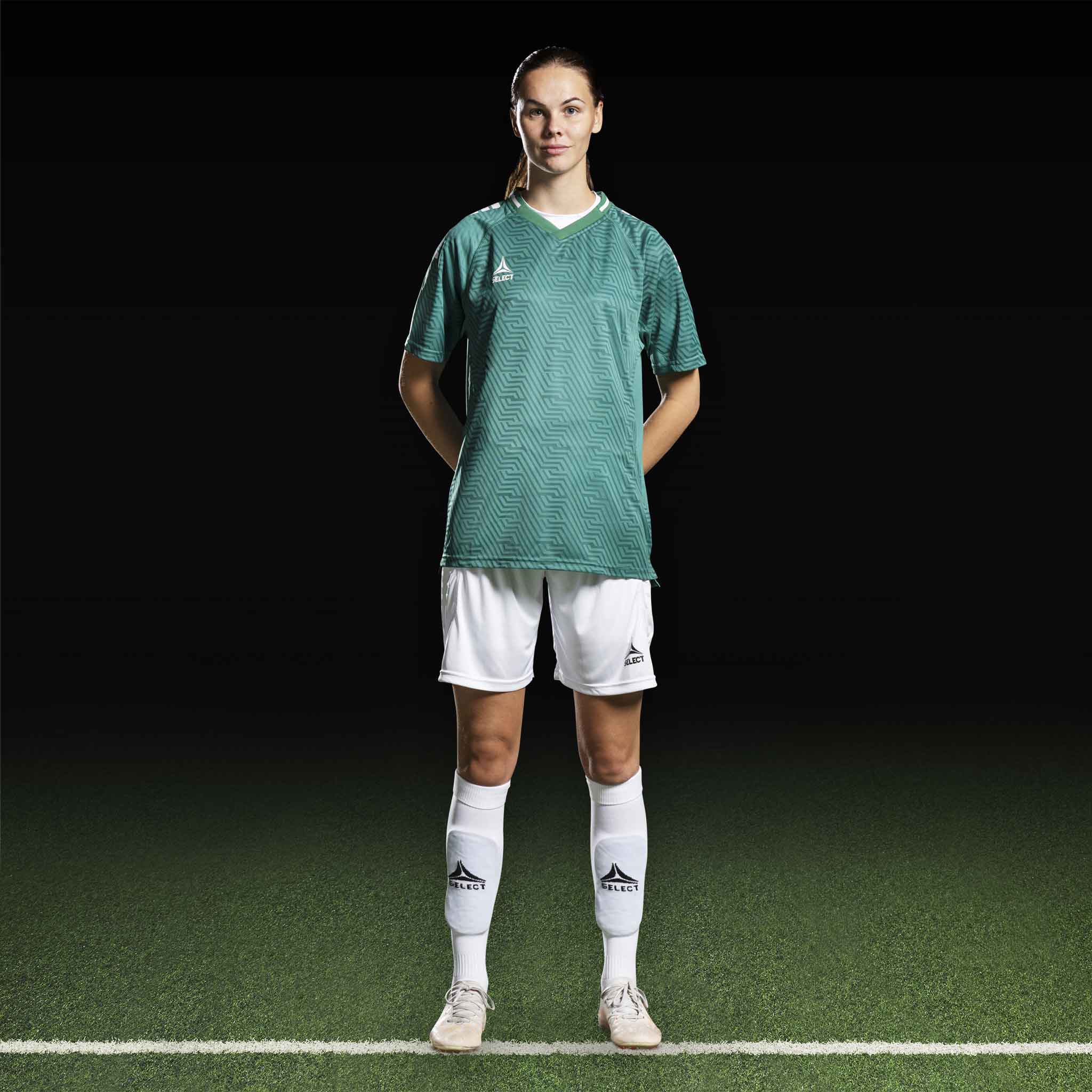 Kvinnelig fotballspiller i grønn Player shirt S/S Monaco v24 og hvite shorts, Match & Training wear, forfra.