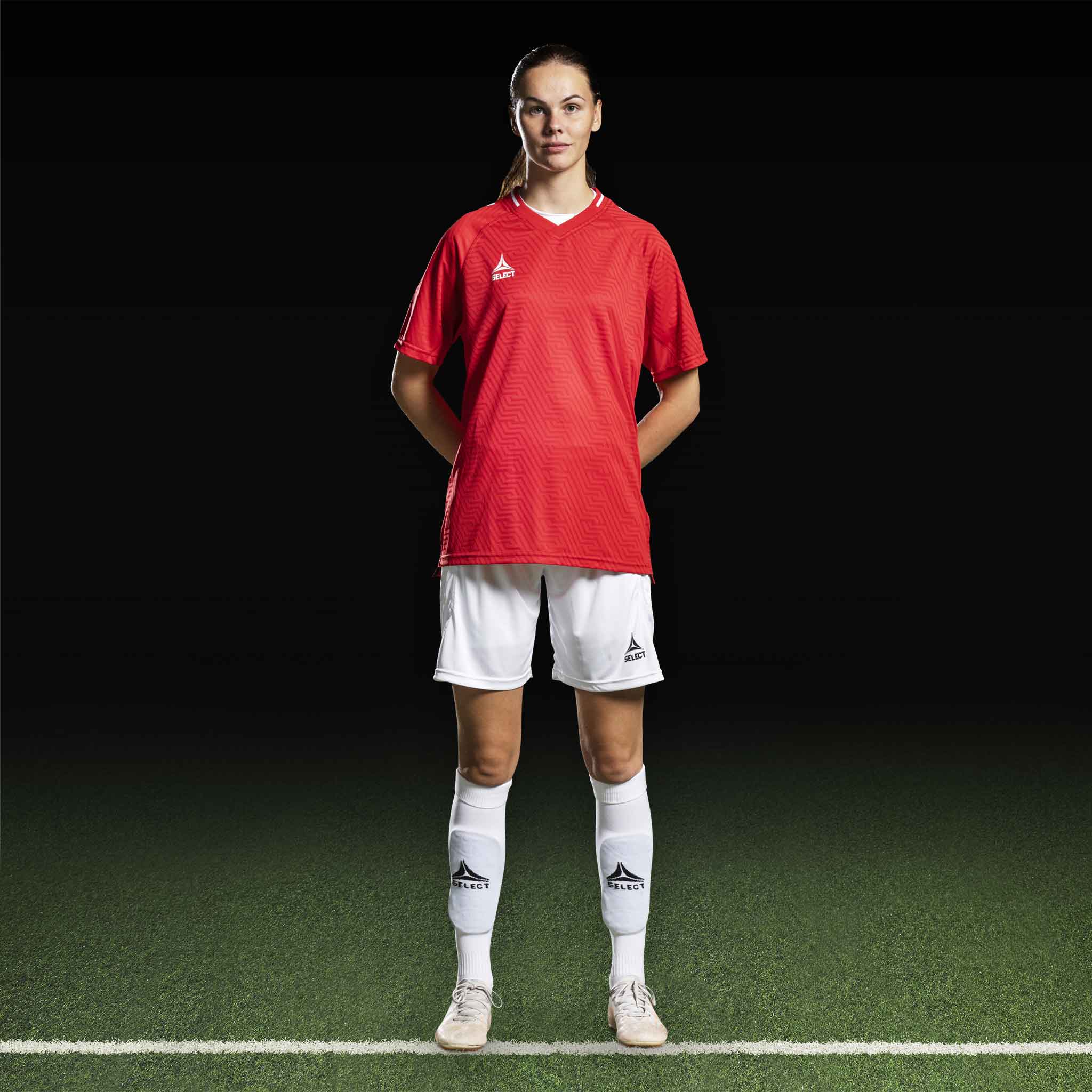 Kvinnelig fotballspiller i rød Player shirt S/S Monaco v24, hvite shorts og strømper. Match & Training wear, forfra.