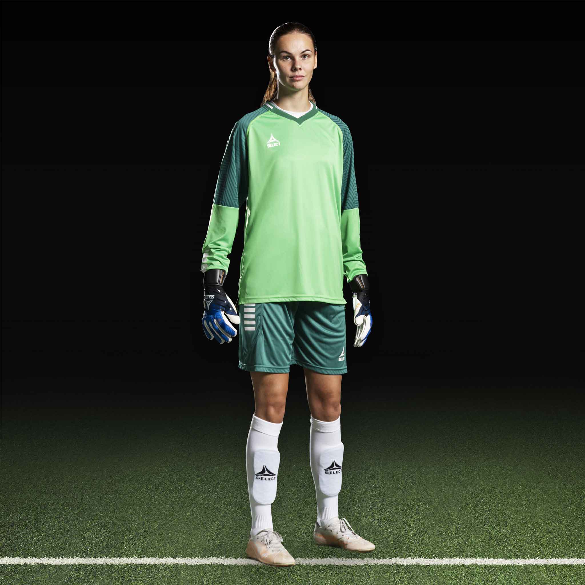 Kvinnelig fotballspiller i grønn Goalkeeper shirt Monaco v24, keeperklær med hansker på banen.