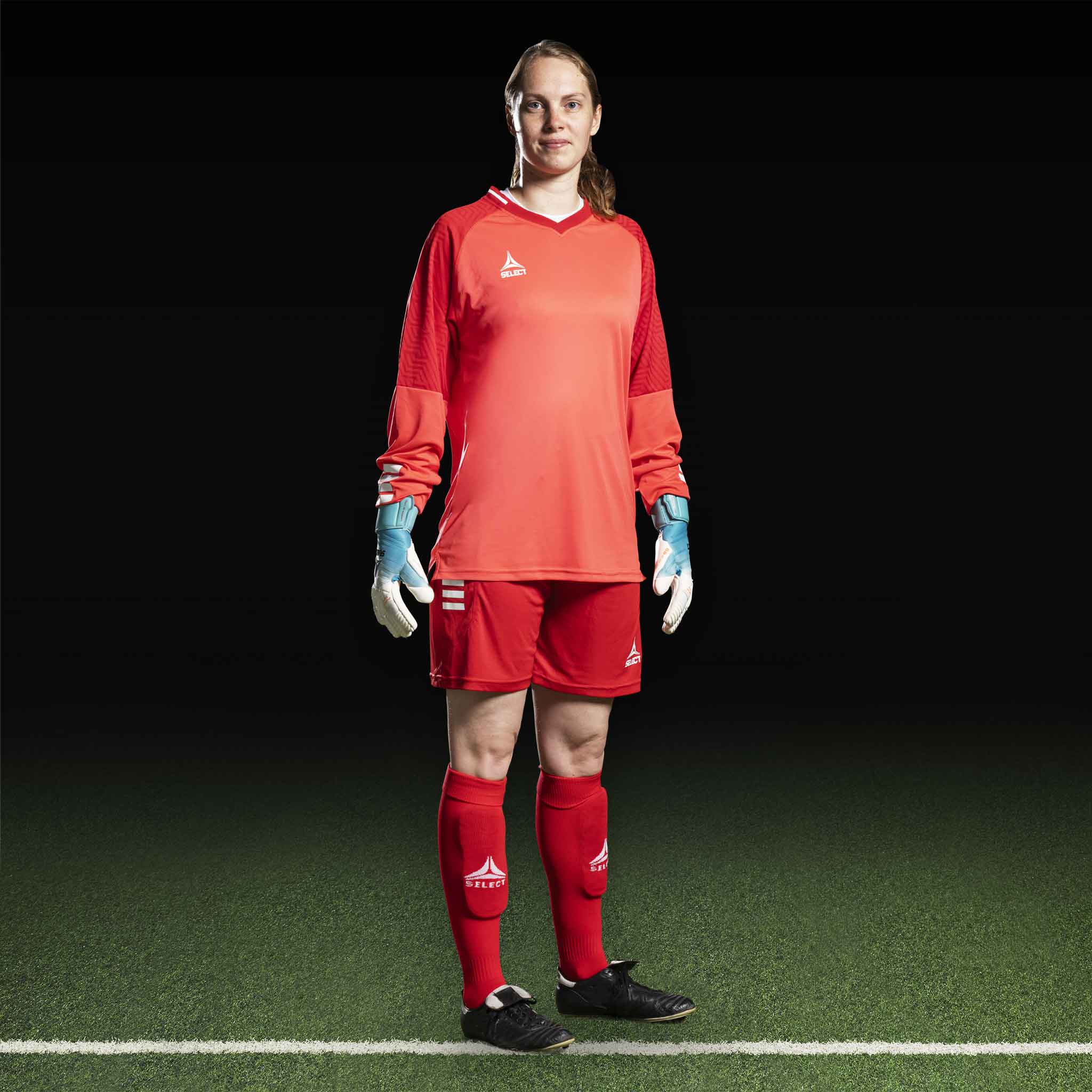 Kvinnelig fotballspiller i rød Goalkeeper shirt Monaco v24, keeperutstyr, sett forfra med matchende shorts, strømper og hansker.