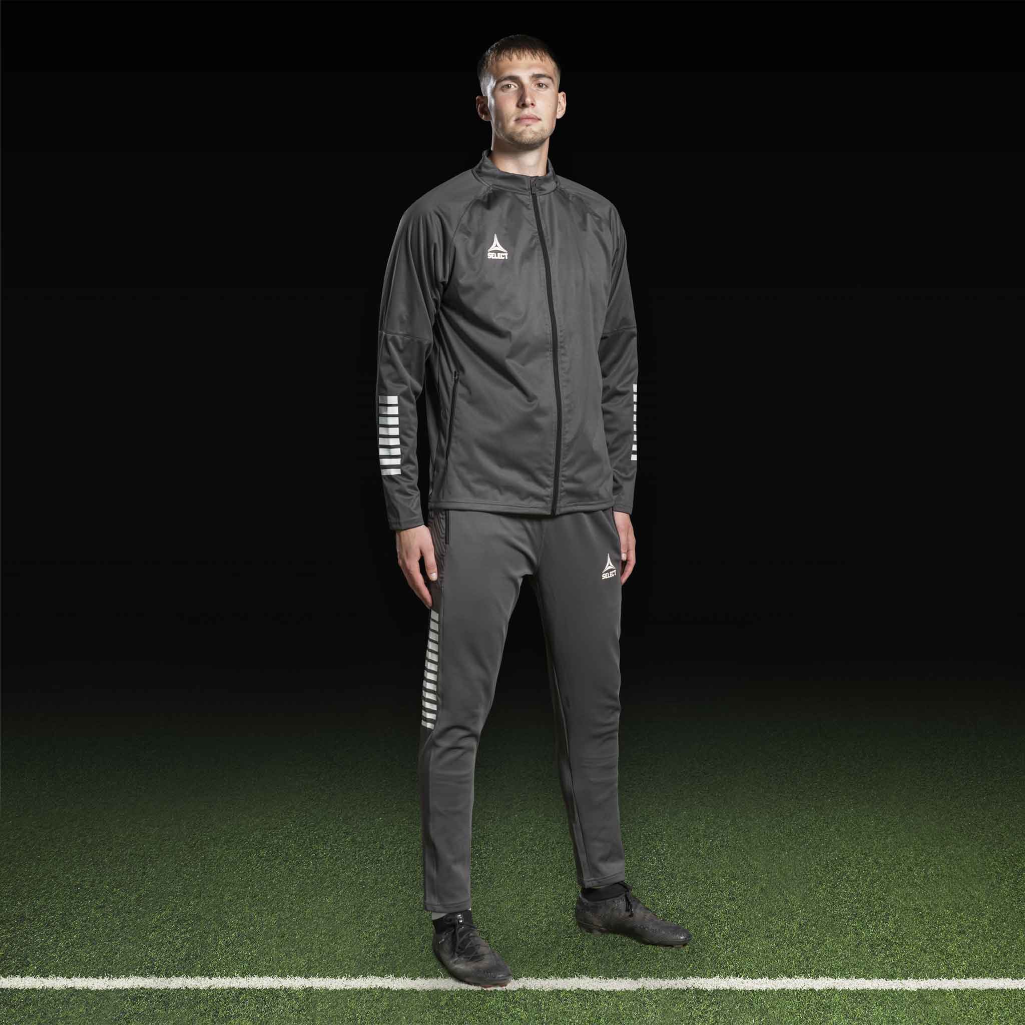 Mannlig fotballspiller i grå og hvit Training jacket Monaco v24, Match & Training wear, forfra på banen.
