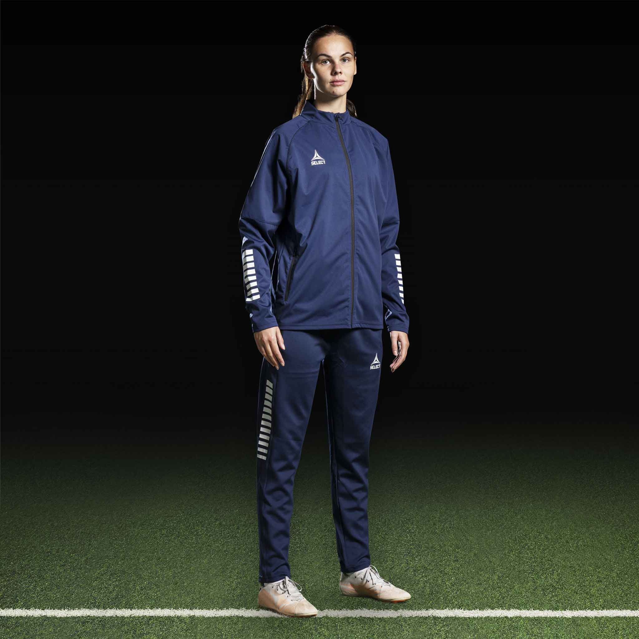 Kvinnelig fotballspiller i marineblå og hvit Training jacket Monaco v24, Match & Training wear, sett forfra.