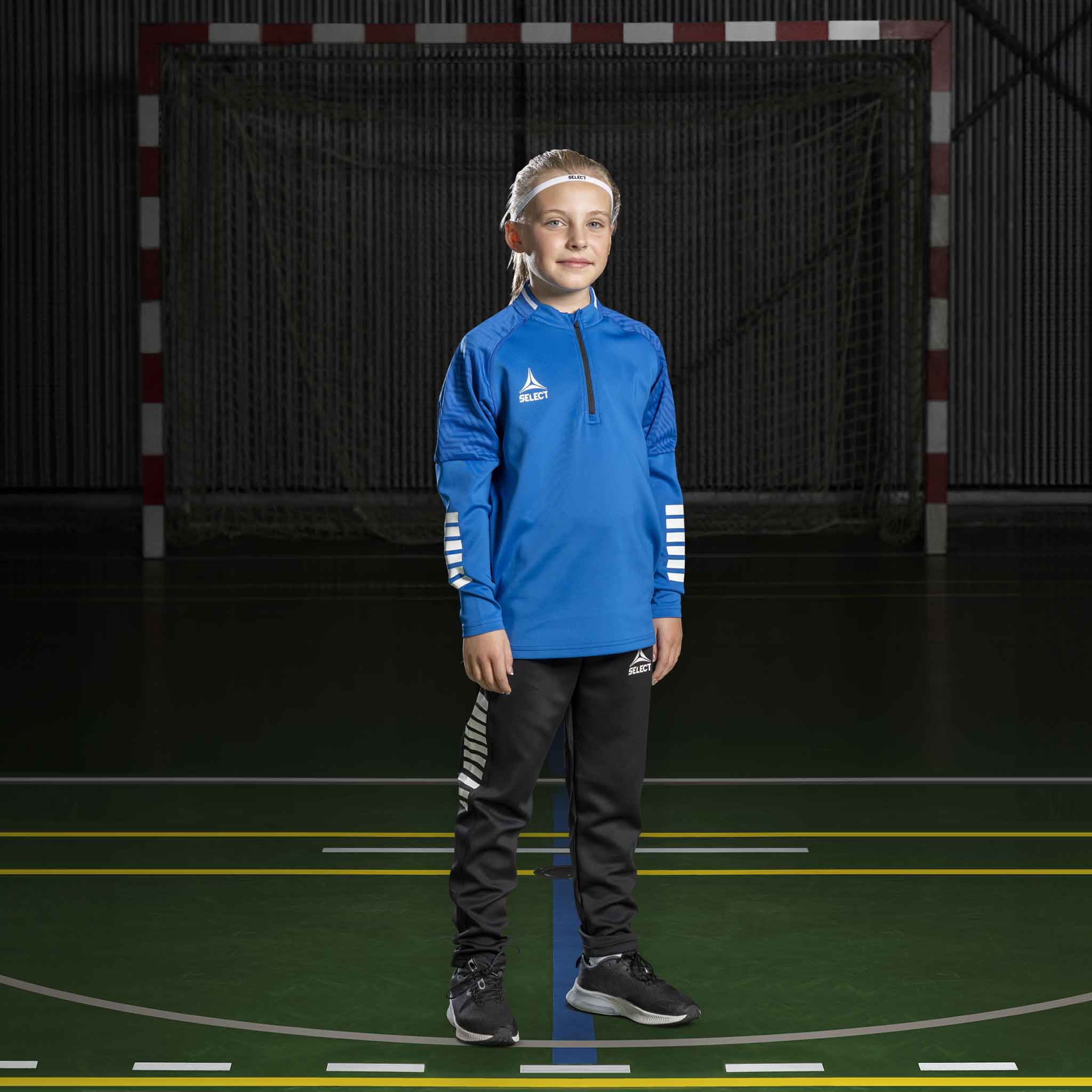 Håndballgutt i blå Training sweat 1/2 zip Monaco v24, svarte bukser. Match & Training wear, forfra.