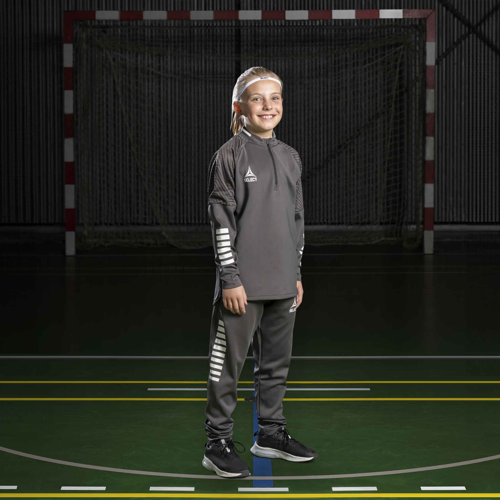 Jente håndballspiller i grå Training sweat 1/2 zip Monaco v24, Match & Training wear, med hvite detaljer på banen.