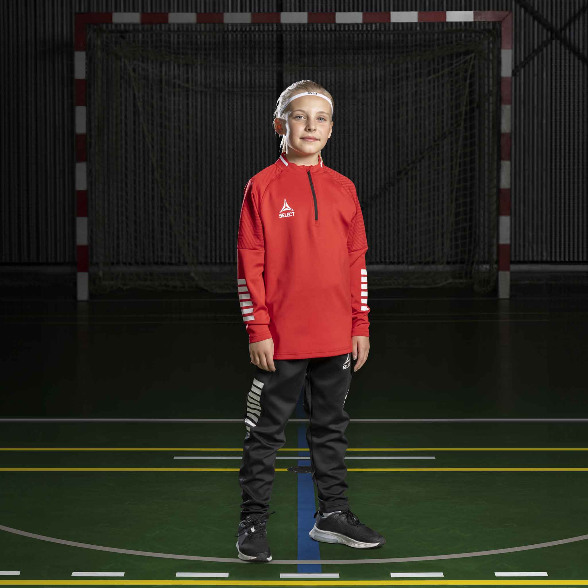 Håndballgutt i rød Training sweat 1/2 zip Monaco v24, Match & Training wear, med svarte bukser på banen.