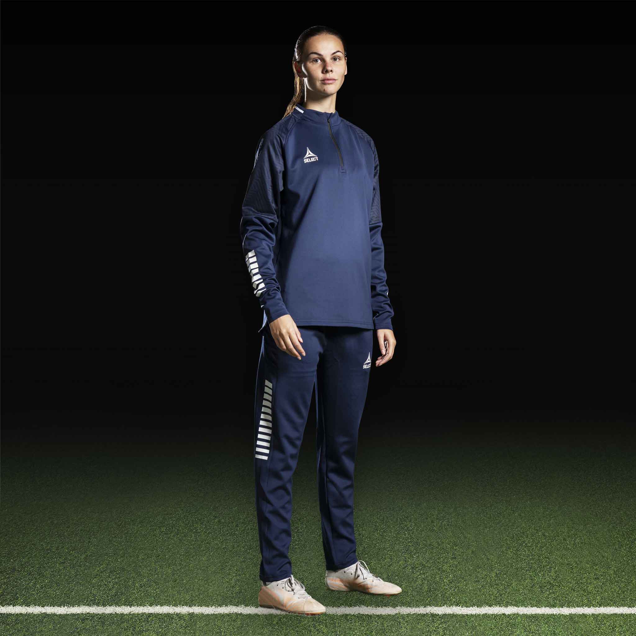 Kvinnelig fotballspiller i marineblå Training sweat 1/2 zip Monaco v24, Match & Training wear, med hvite detaljer, forfra.