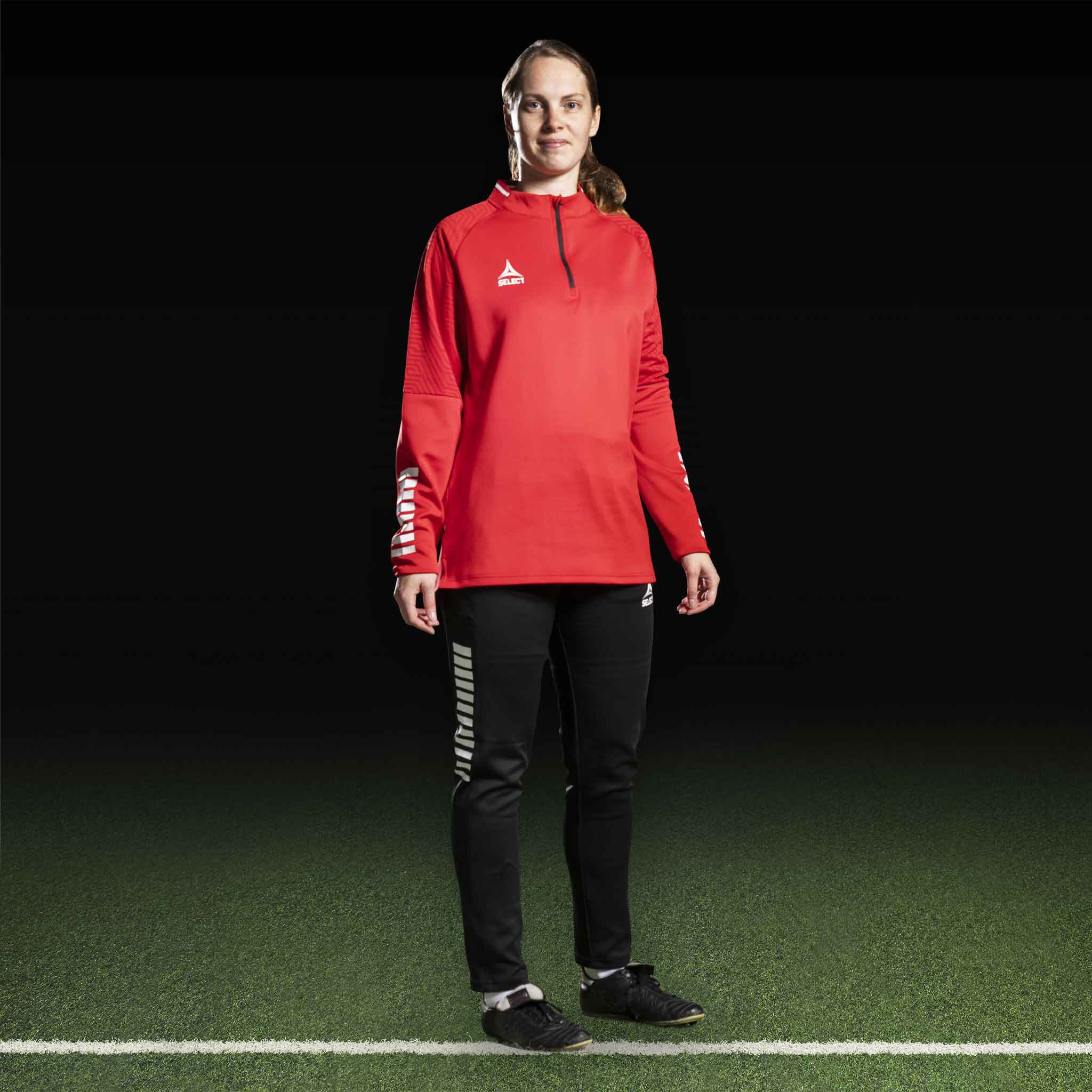 Kvinnelig fotballspiller i rød Training sweat 1/2 zip Monaco v24 og sorte bukser, Match & Training wear.