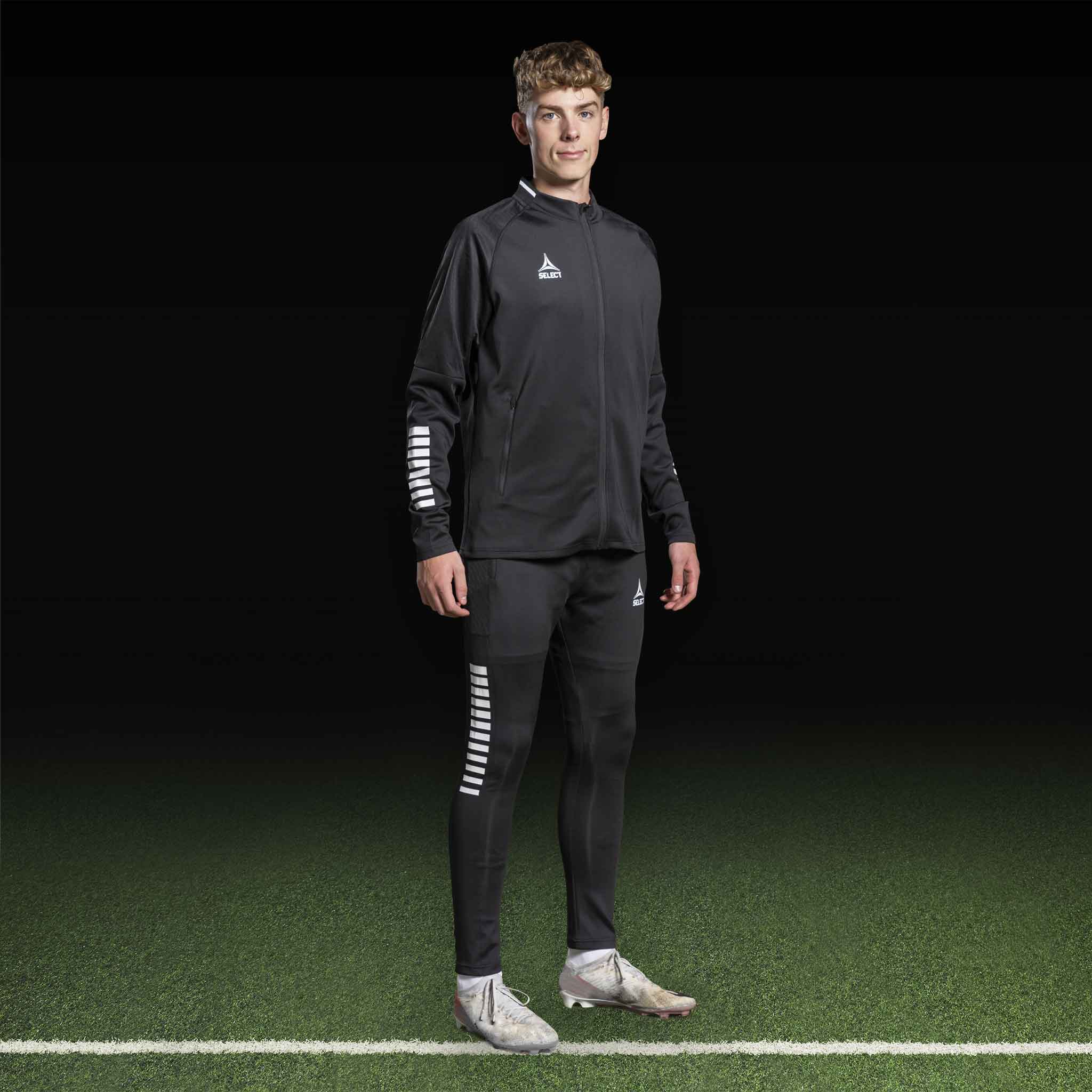Mannlig fotballspiller i sort-hvit Zip jacket Monaco v24, Match & Training wear, sett forfra på banen.