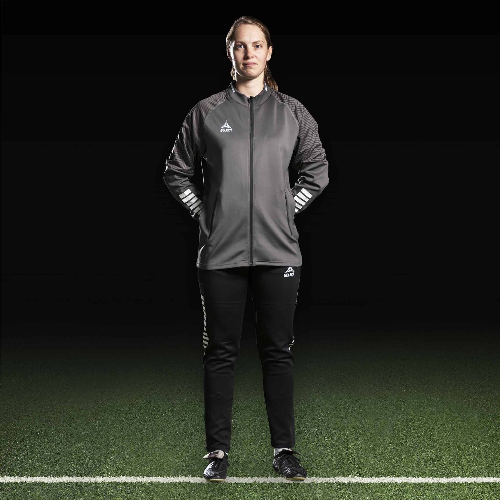Kvinnelig fotballspiller i grå Zip jacket Monaco v24 og sorte bukser, Match & Training wear, forfra.