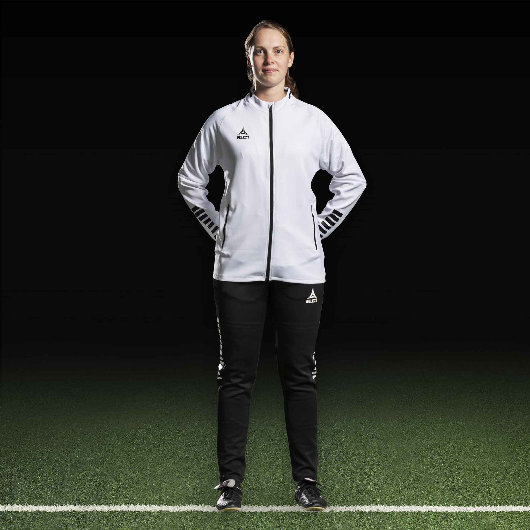 Kvinnelig fotballspiller i hvit Zip jacket Monaco v24 og sorte bukser, Match & Training wear, forfra.