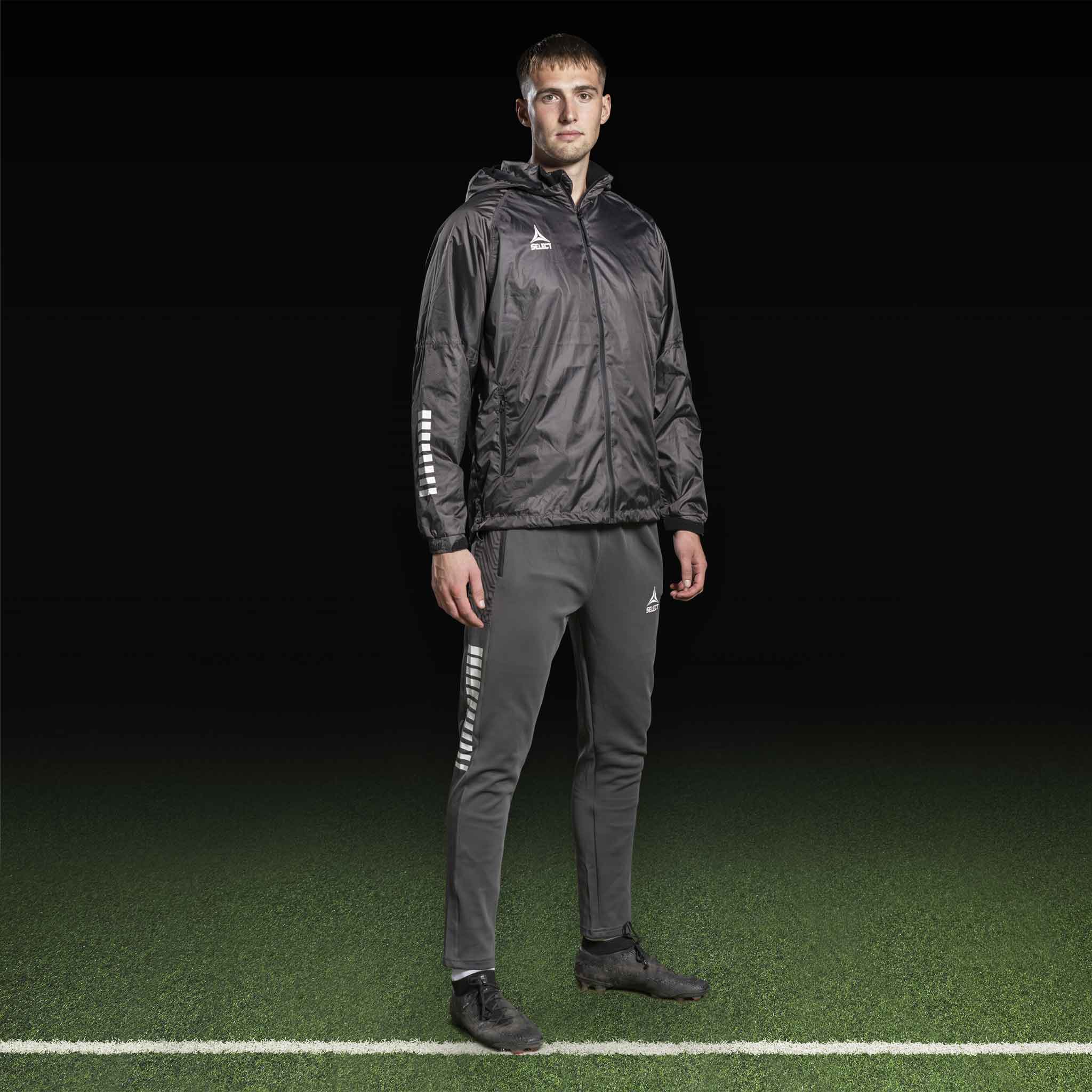 Mannlig fotballspiller i grå Training pants Regular Fit Monaco v24 og svart jakke, Match & Training wear, sett forfra.