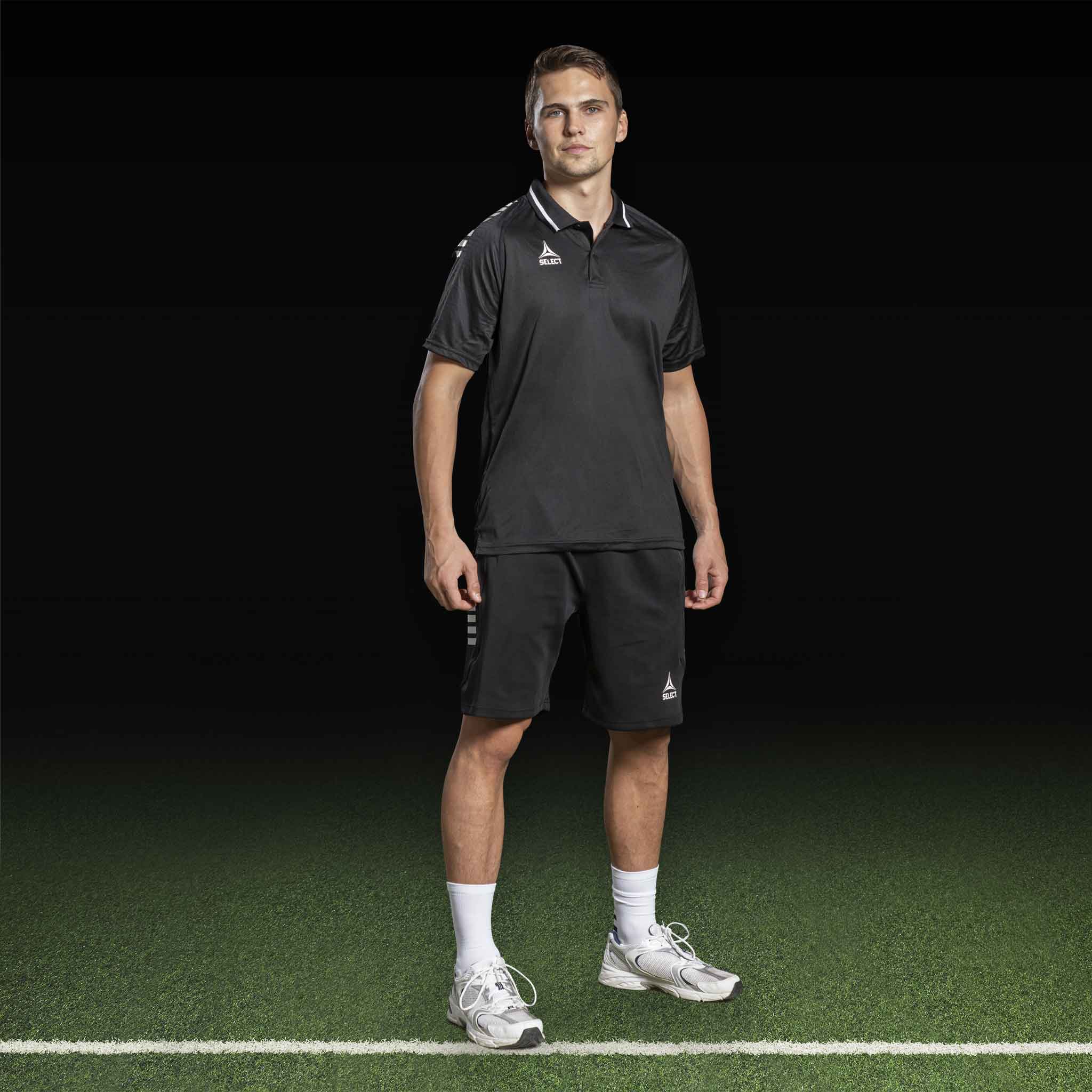 Mannlig fotballspiller i sorte Bermuda shorts Monaco v24 fritidsklær, sett forfra på banen.