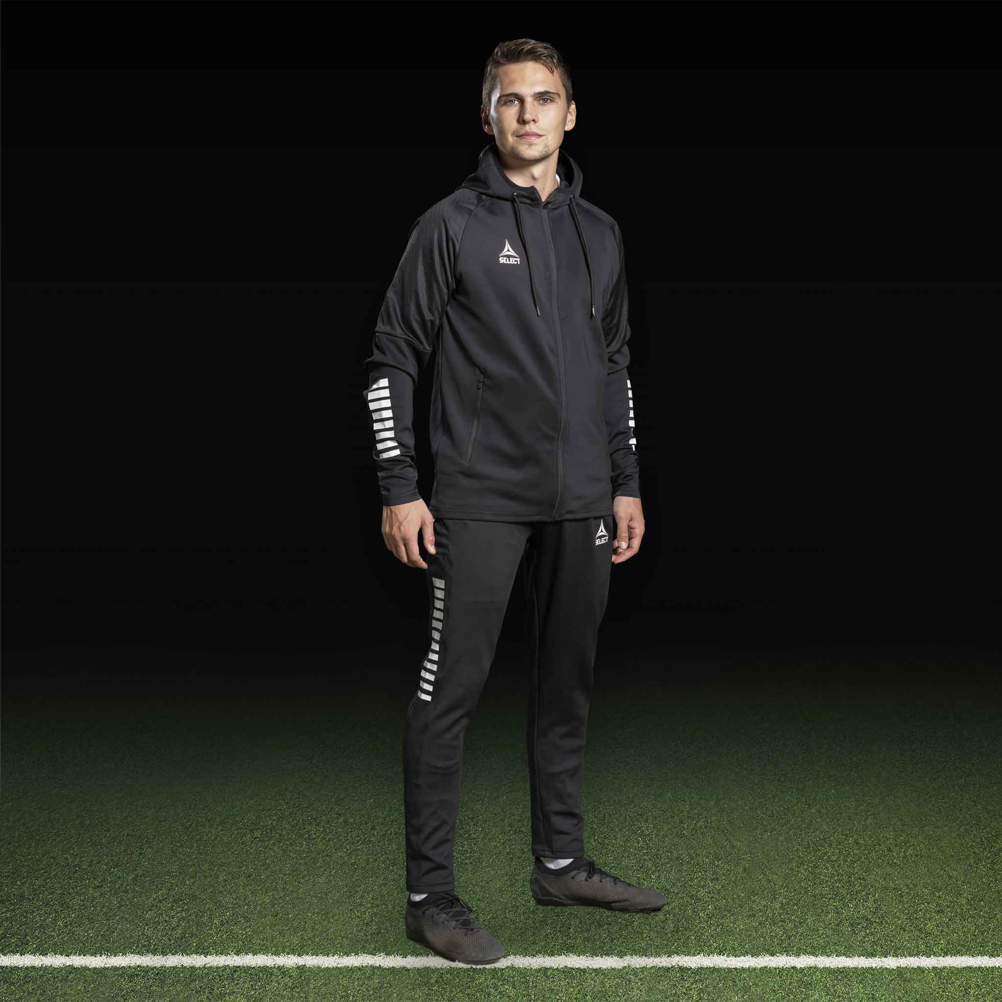 Mannlig fotballspiller i sort Zip hoodie Monaco v24, Match & Training wear, med hvite detaljer på ermene.