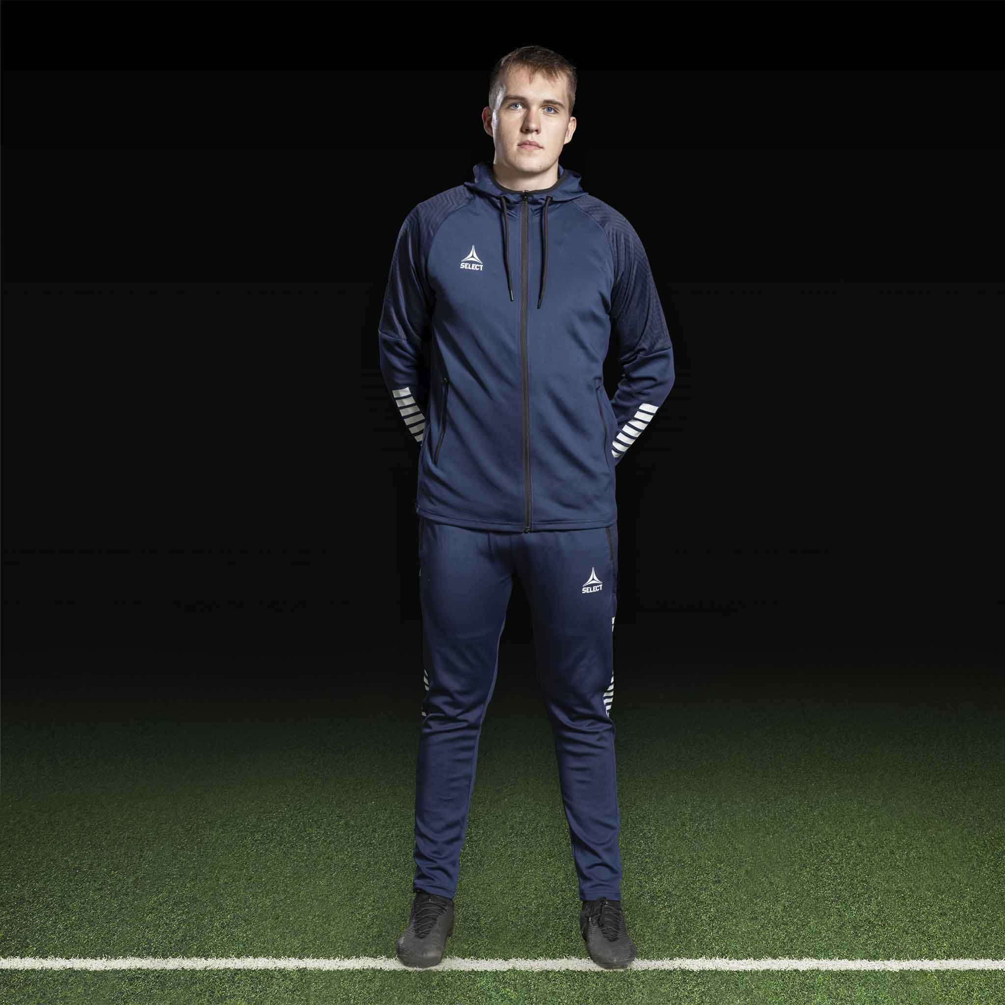 Mannlig fotballspiller i marineblå og hvit Zip hoodie Monaco v24, Match & Training wear, sett forfra.