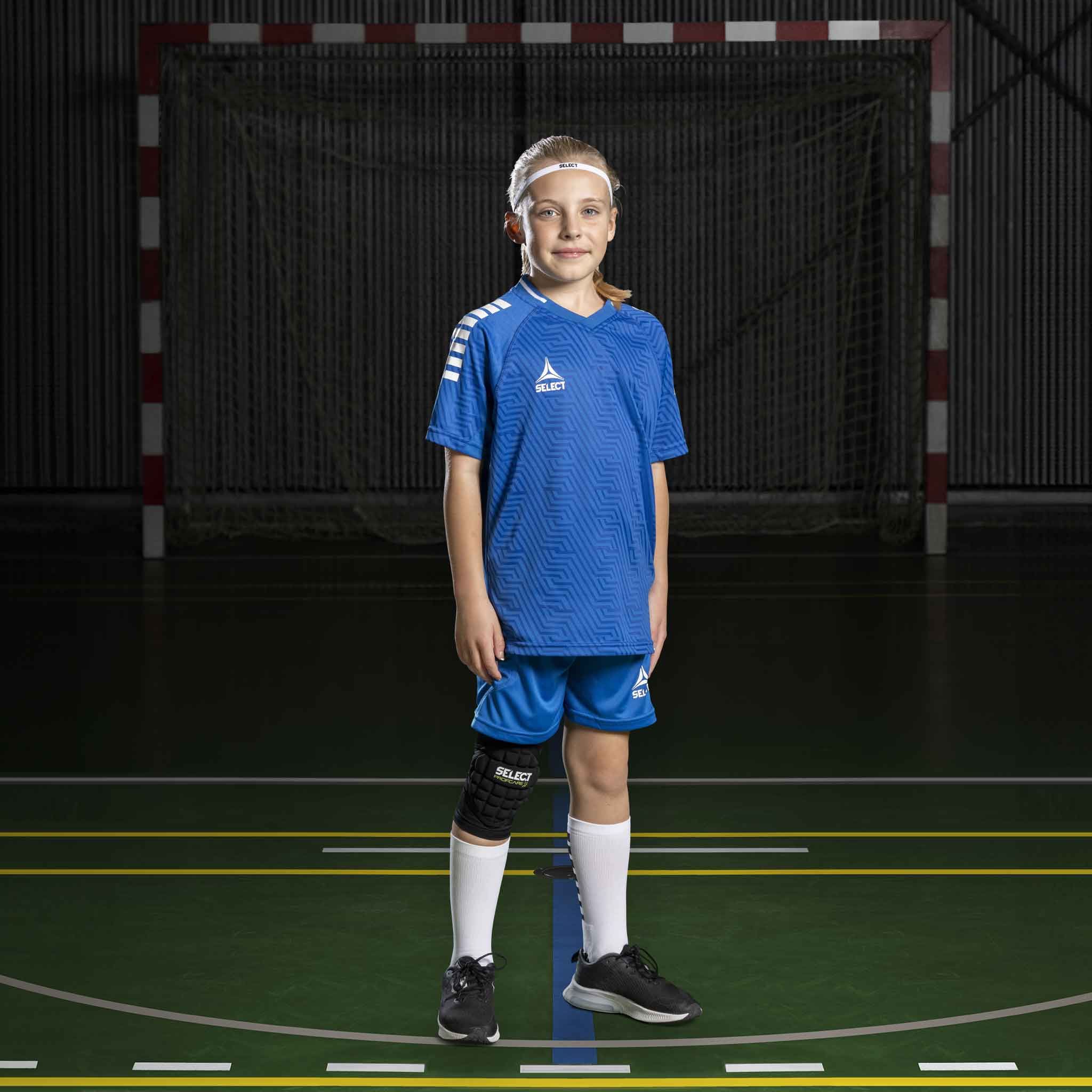 Jente håndballspiller i blå og hvite Player shorts Monaco v24, Match & Training-tøy, forfra på banen.