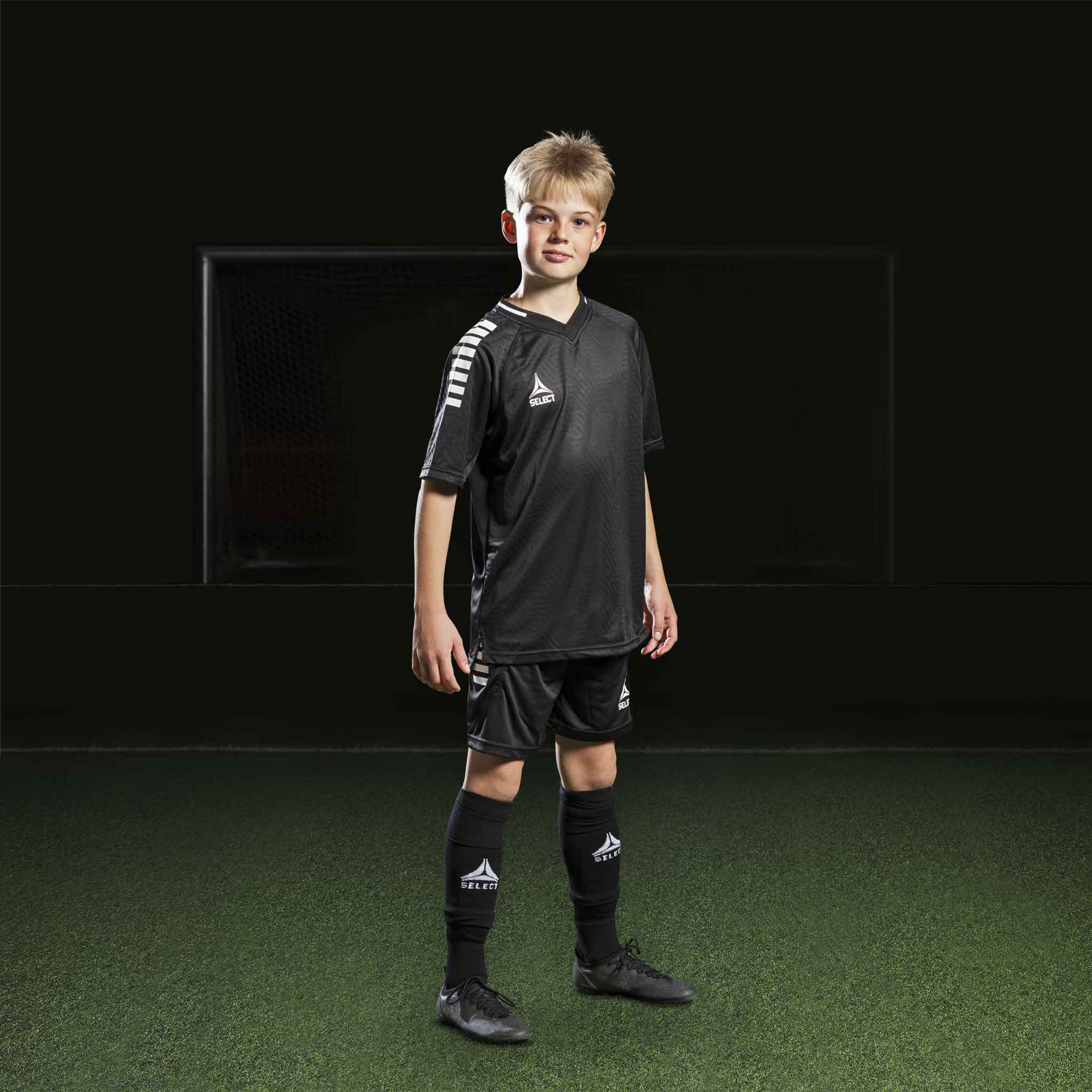 Gutt fotballspiller i sorte Player shorts Monaco v24, Match & Training wear, med matchende trøye og strømper.