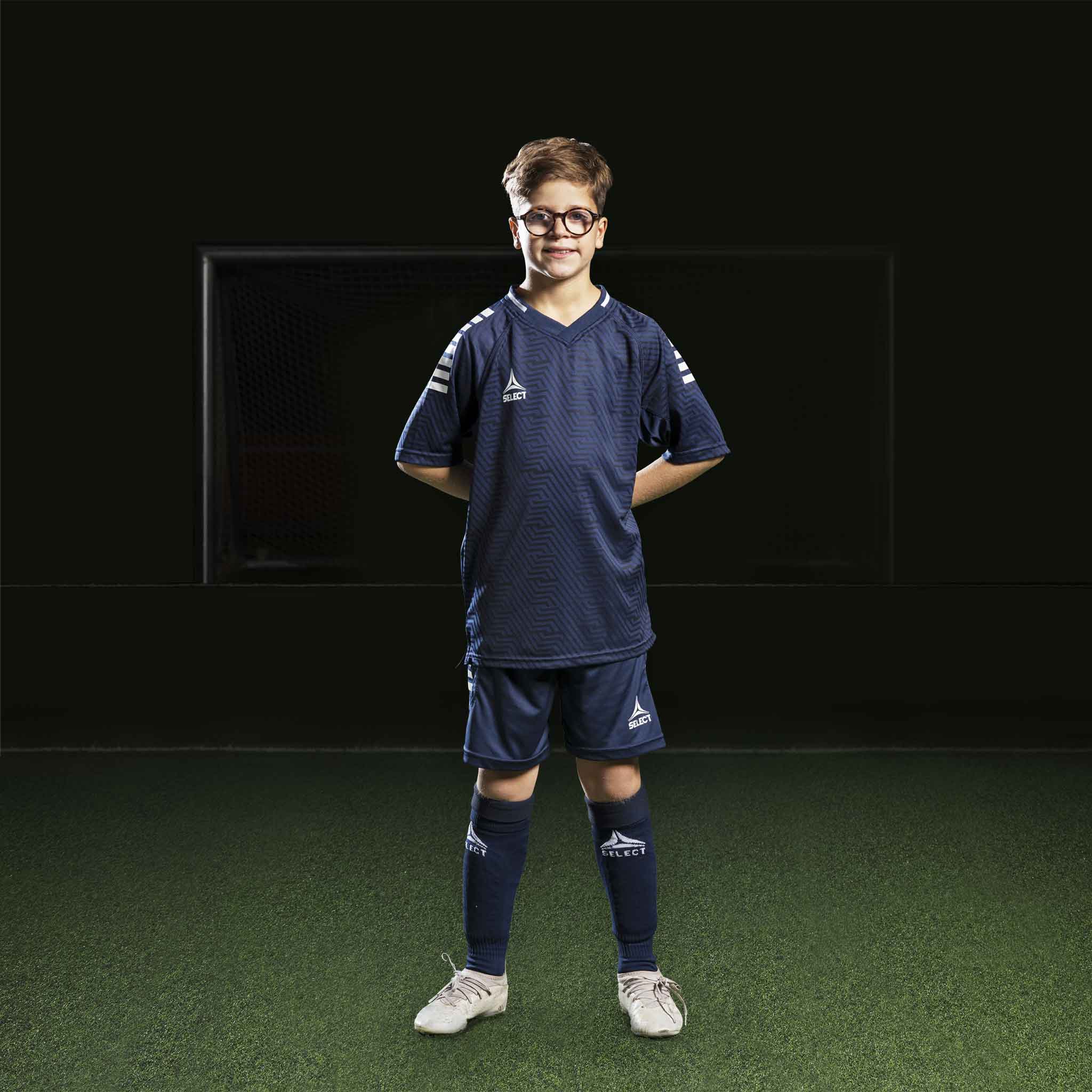 Gutt fotballspiller i marineblå og hvite Player shorts Monaco v24, Match & Training-klær, forfra.