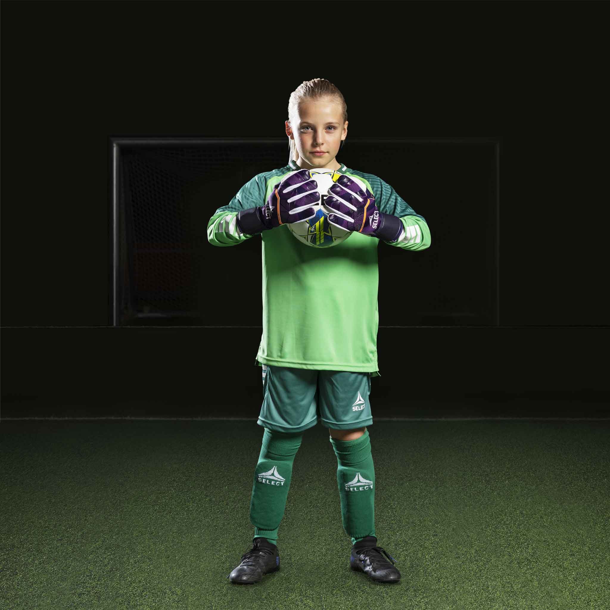 Ung fotballspiller i grønn Goalkeeper shirt Monaco v24, keeperklær, med matchende hansker og shorts.
