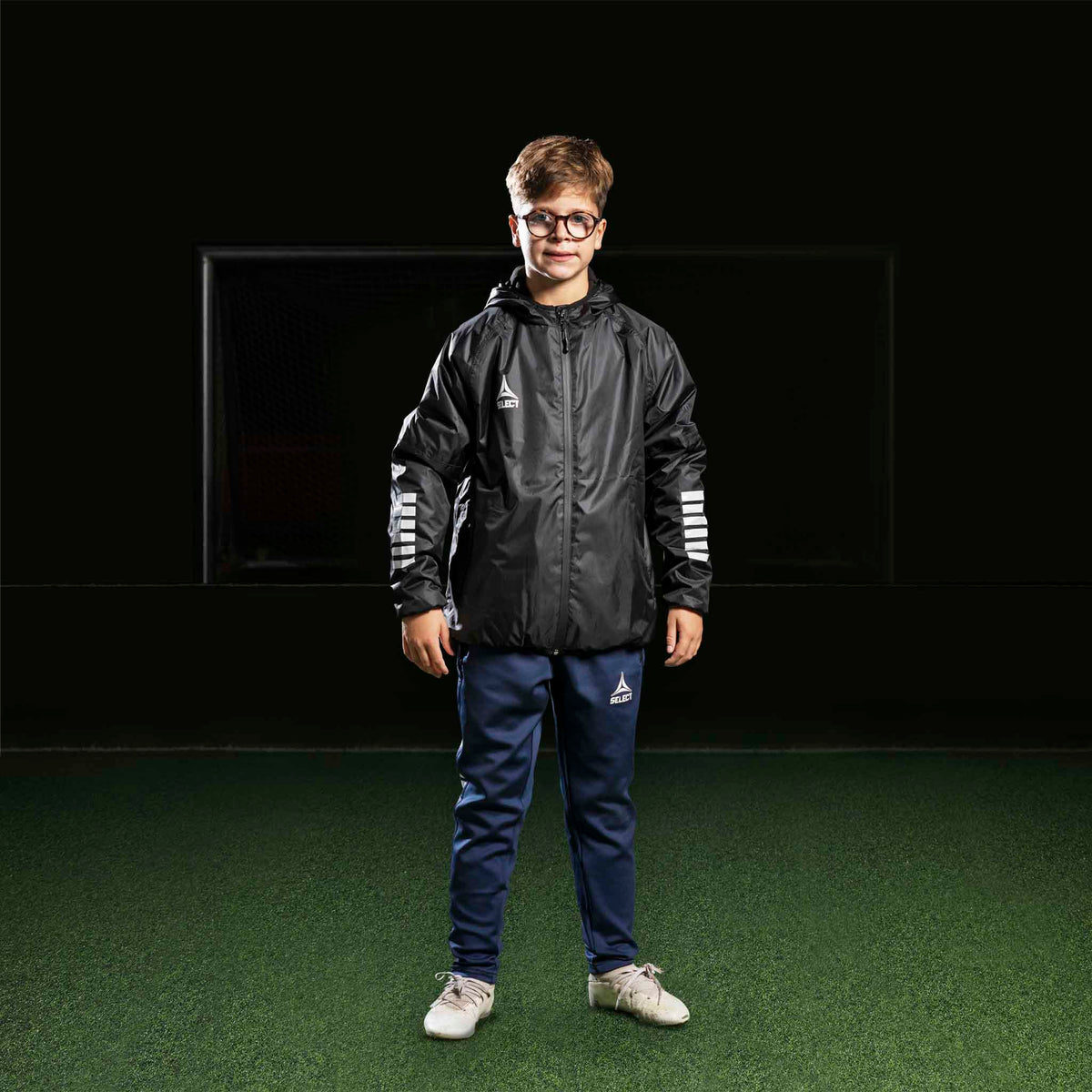 Gutt fotballspiller i marineblå Training pants Regular Fit Monaco v24, sort jakke. Kamp- og treningstøy.