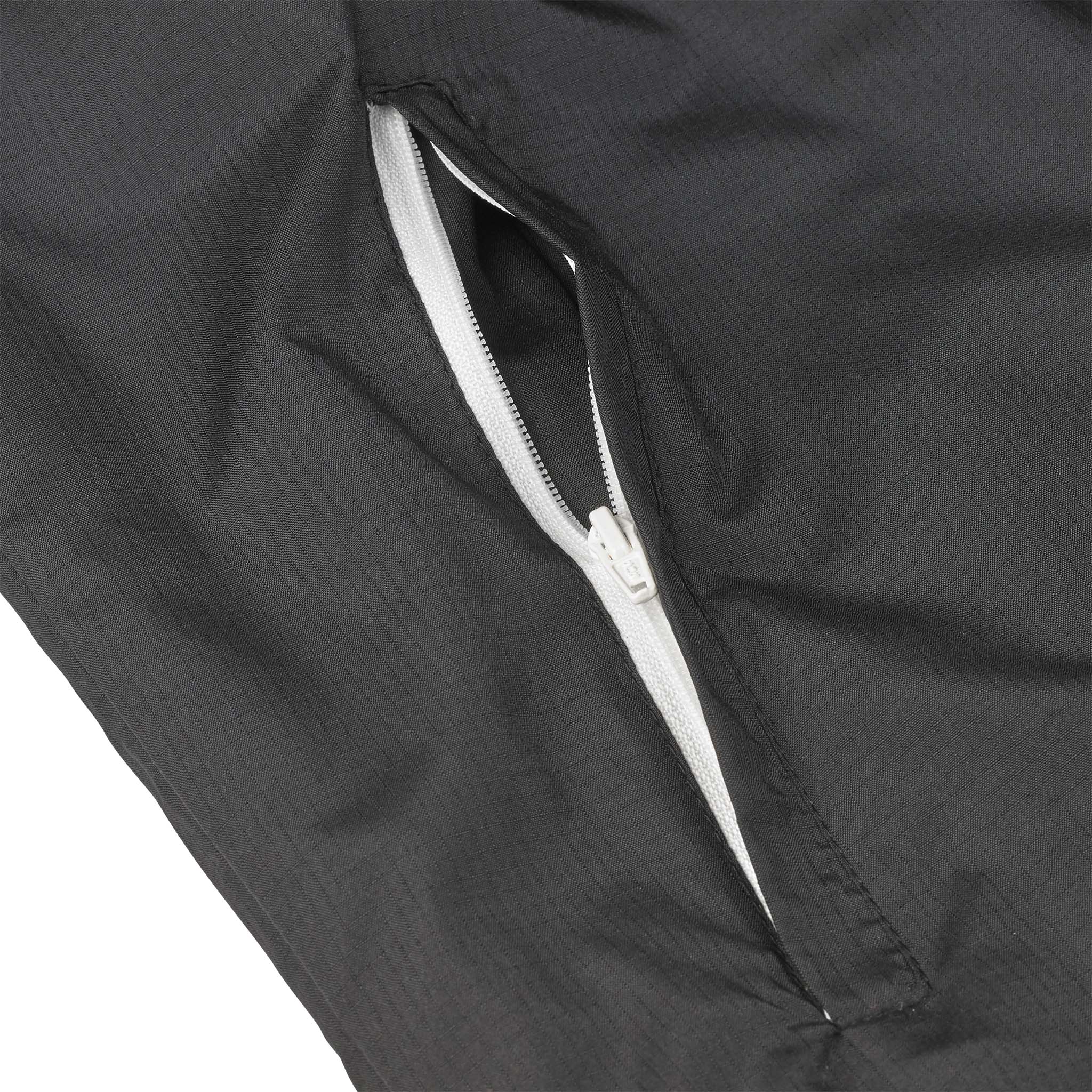 Nærbilde av svart Training jacket Spain v25, Match & Training wear, med detalj av hvit glidelåslomme.