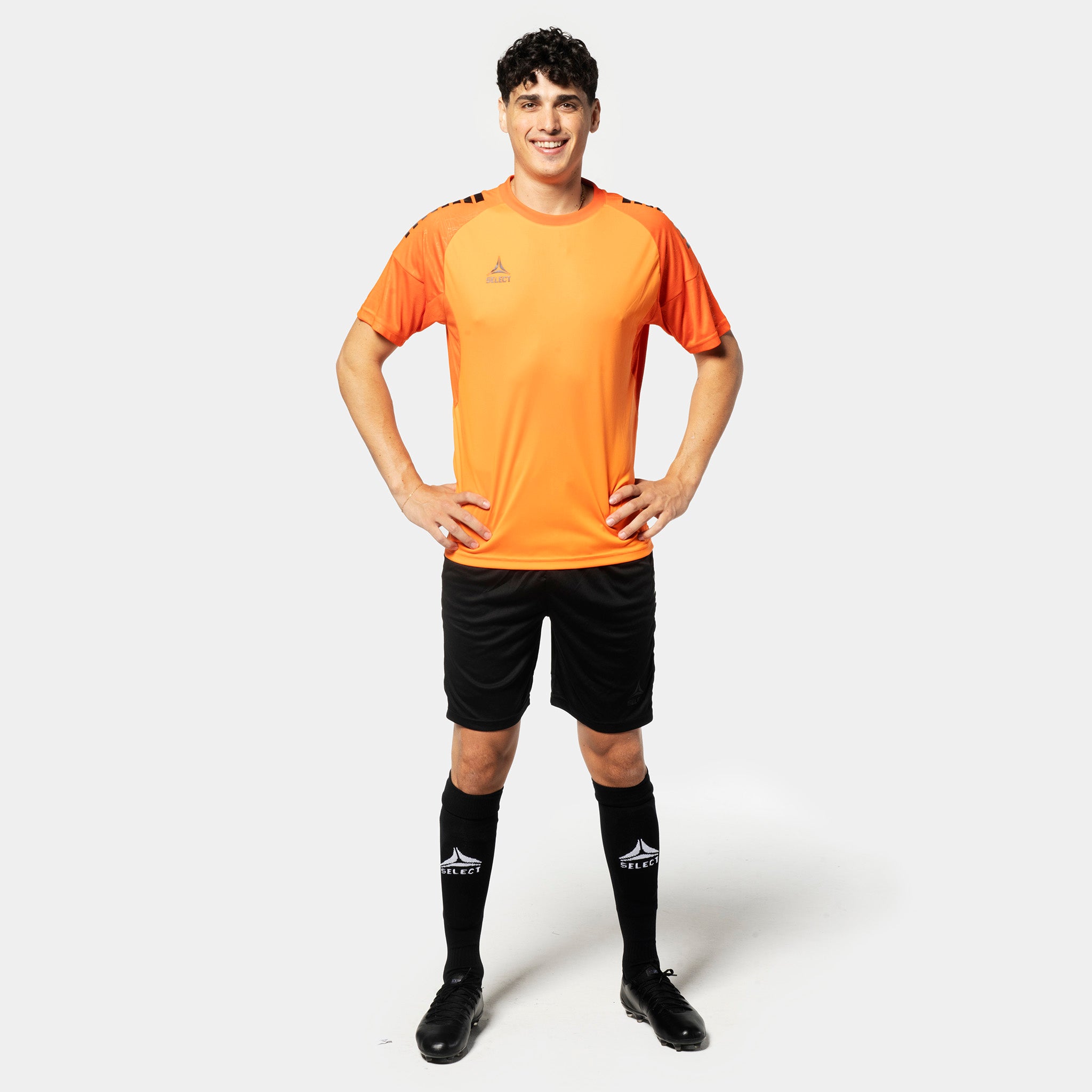 Mannlig fotballspiller i oransje trøye & svarte Player shorts Spain v25, Kamp- & treningsklær, sett forfra
