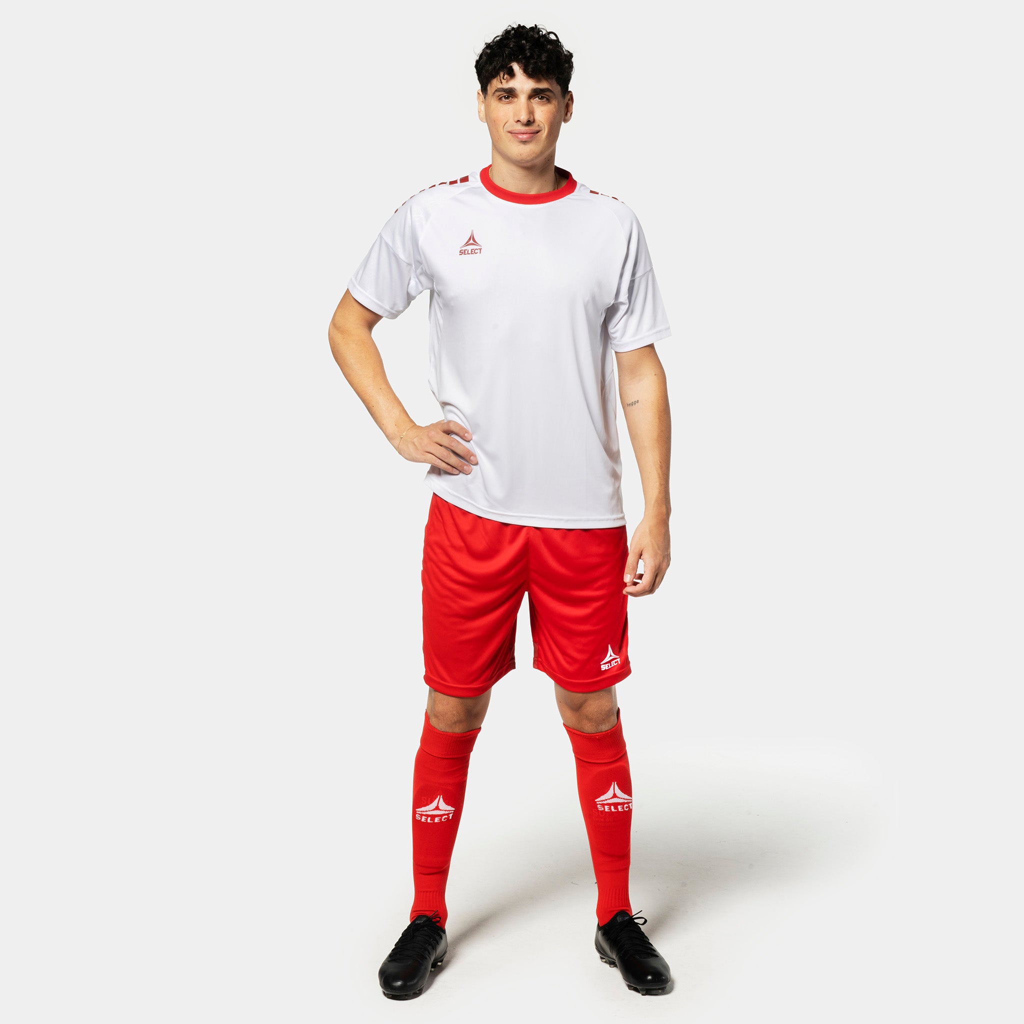 Mannlig fotballspiller i hvit trøye, røde Player shorts Spain v25 og røde strømper. Match & Training wear.