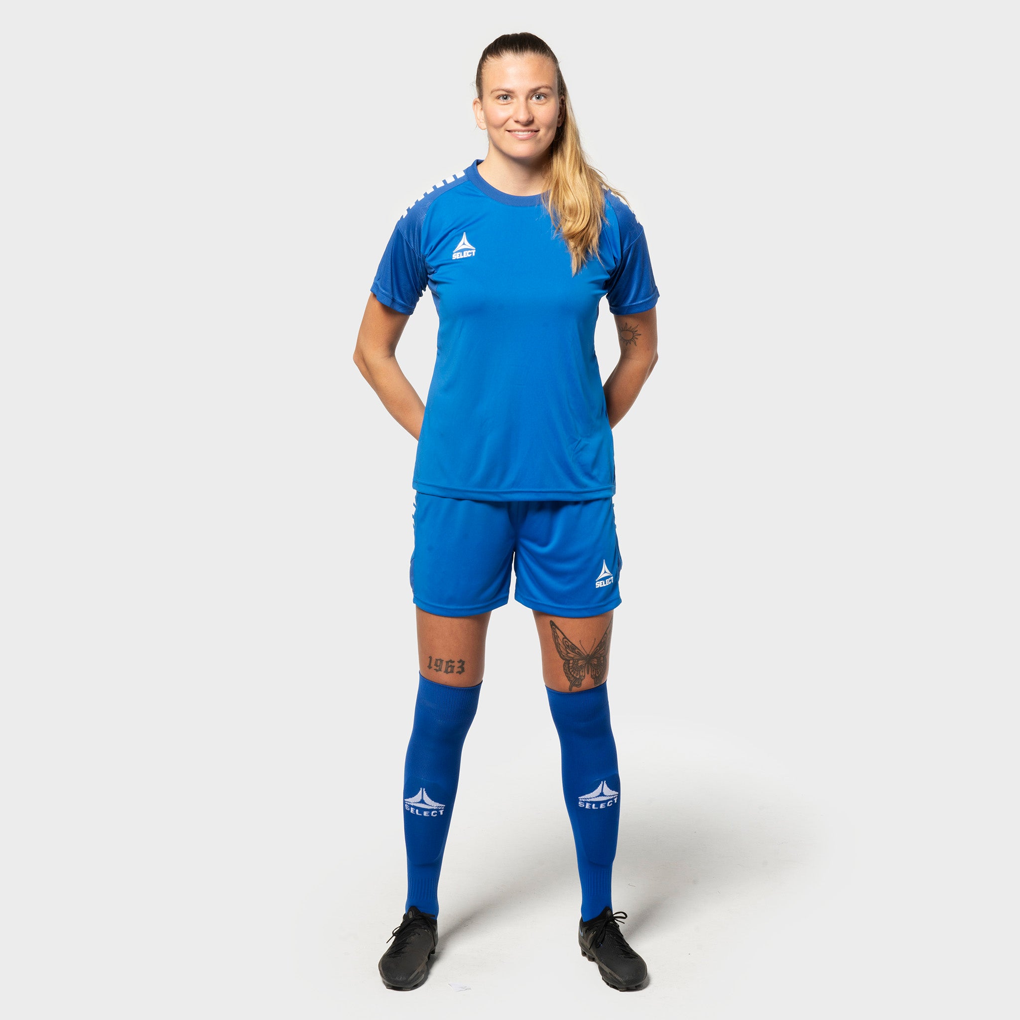 Kvinnelig fotballspiller i blå-hvit Spania v25 trøye og shorts, Match & Training wear, sett forfra.