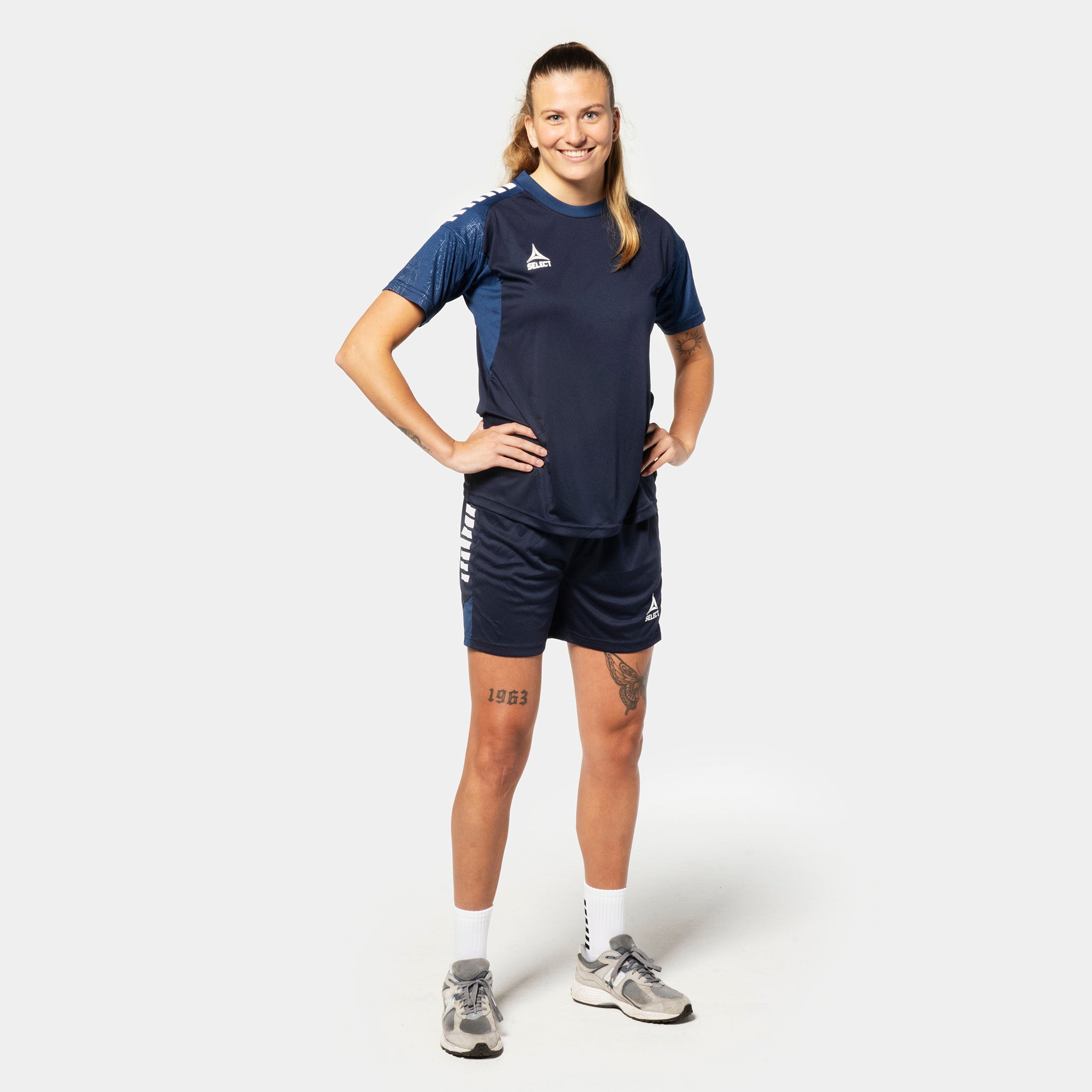 Kvinnelig fotballspiller i marineblå og hvit Player shirt S/S & shorts Spain woman v25, Match & Training wear, sett forfra.