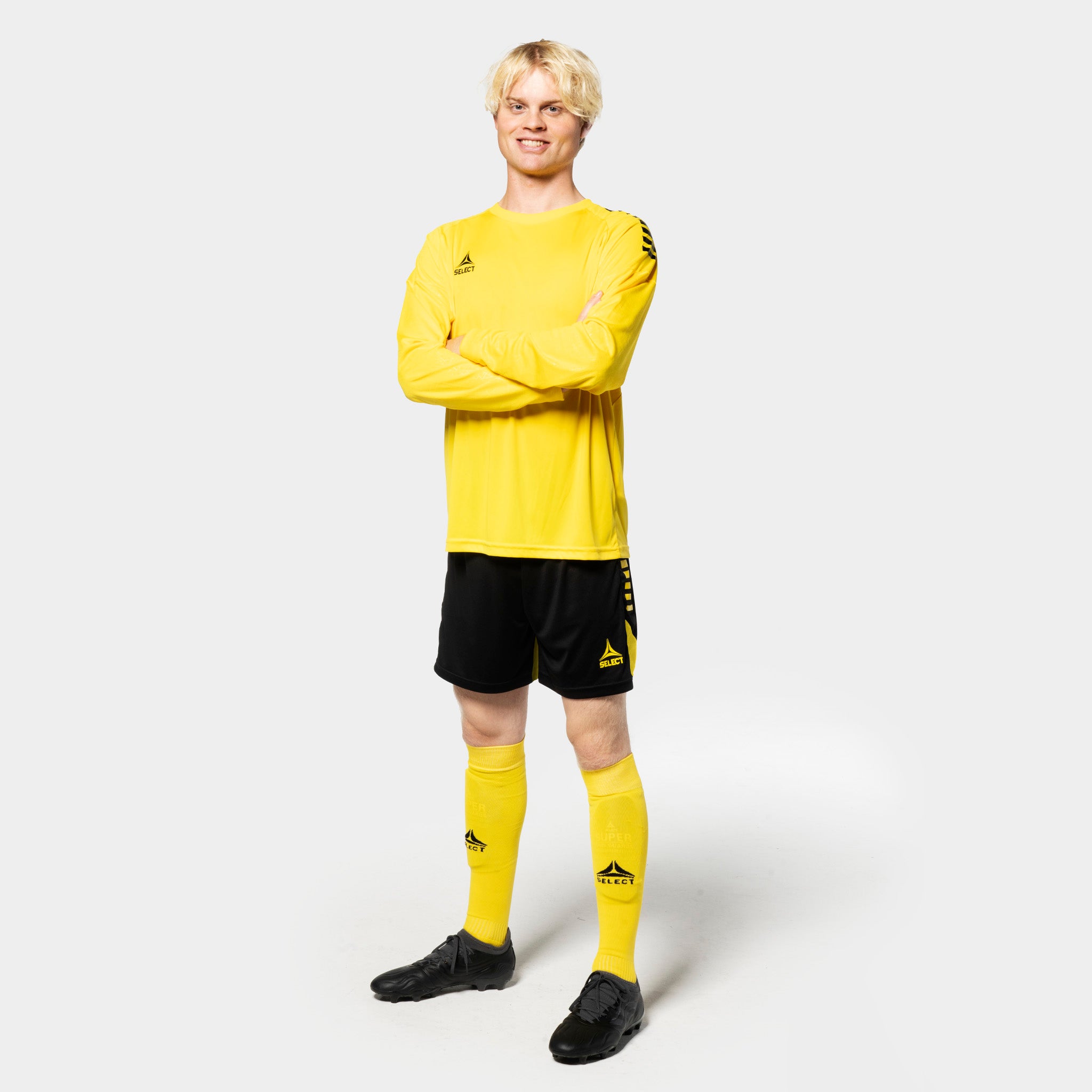 Mannlig fotballspiller i gul Player shirt L/S Spain v25, sorte shorts, gule strømper. Match & Training wear, forfra.