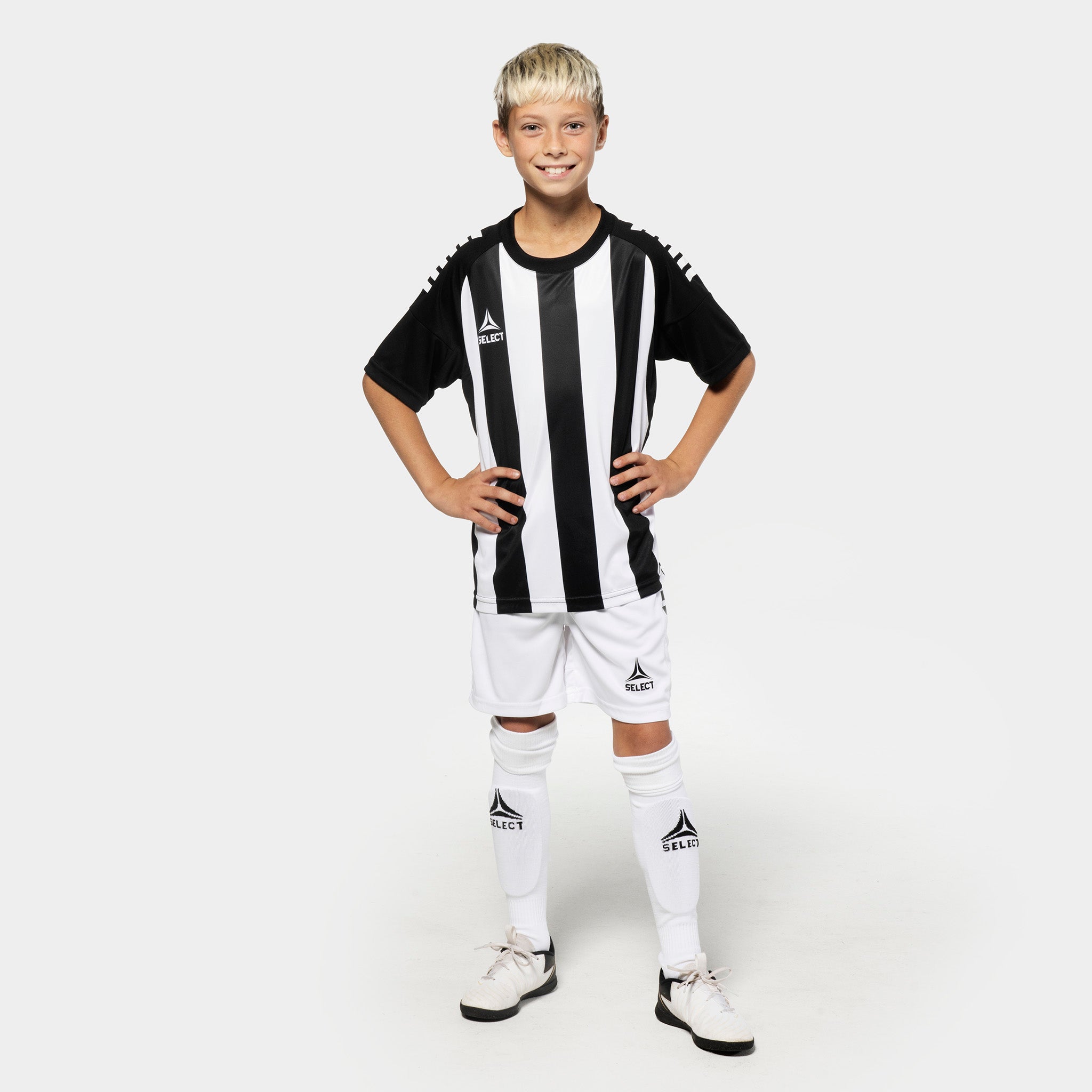 Gutt fotballspiller i sort-hvit stripet Player shirt S/S Spain v25, Match & Training-tøy, med hvite shorts og strømper.