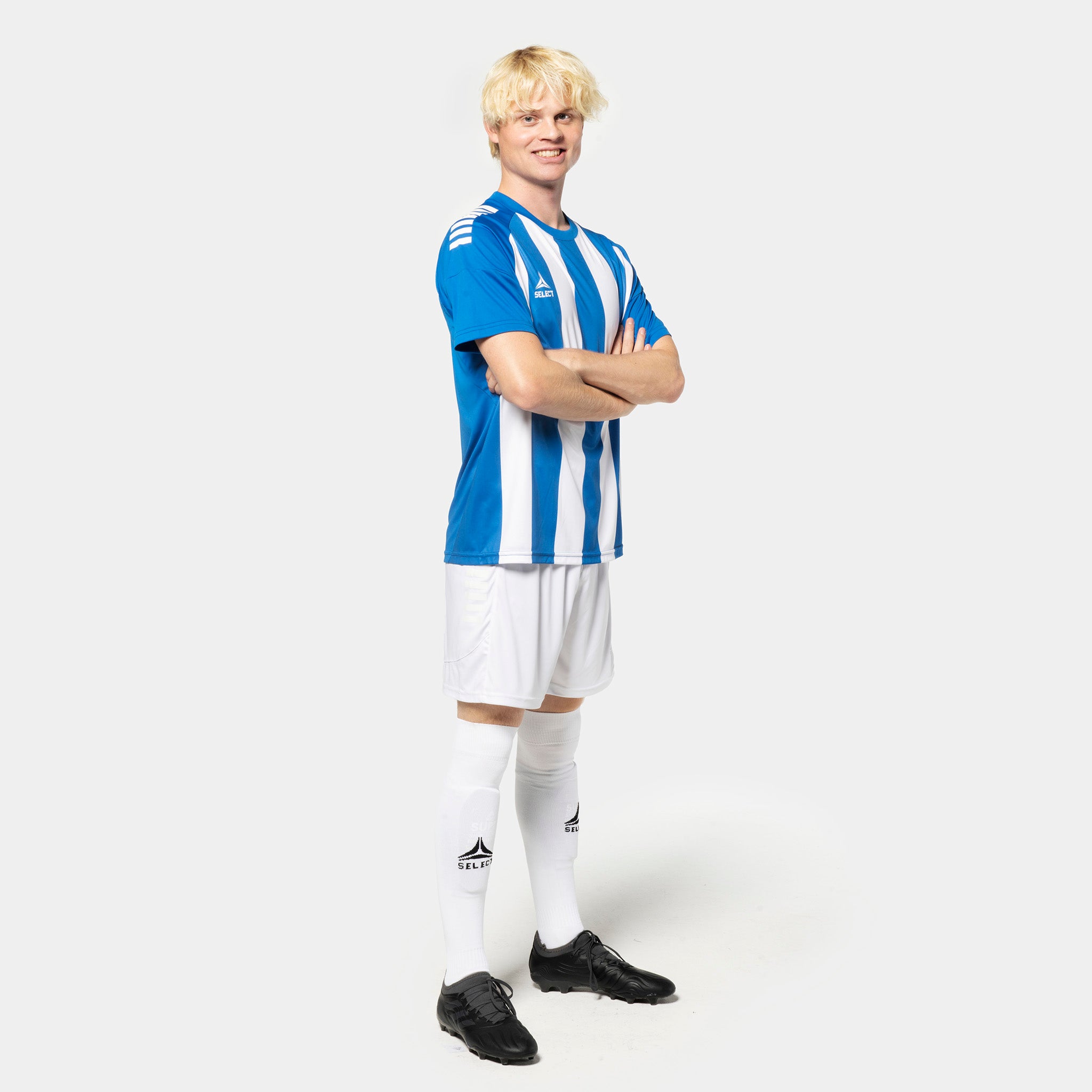 Mannlig fotballspiller i blå- og hvitstripet Player shirt S/S Spain striped v25, hvite shorts og strømper. Match & Training wear.