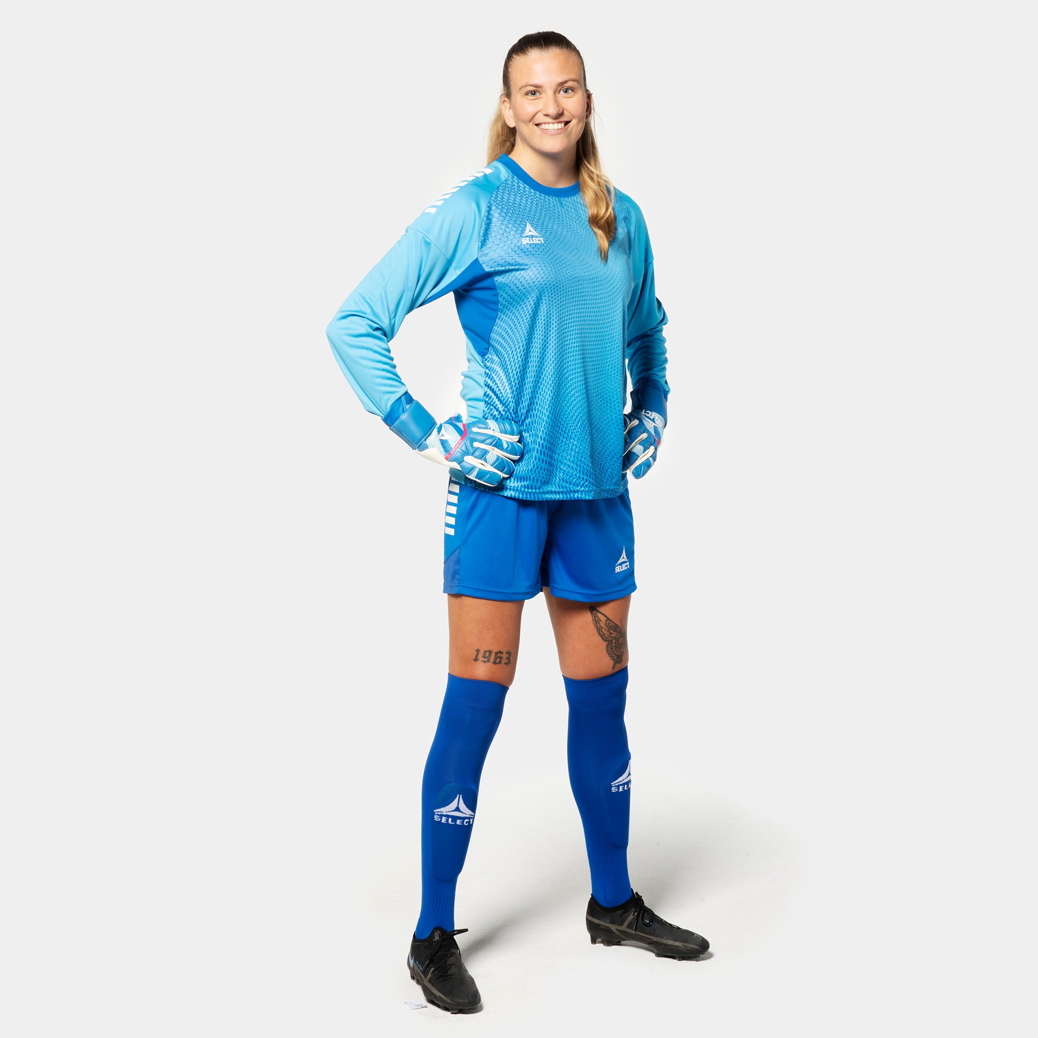 Kvinnelig fotballspiller i blå Goalkeeper shirt Spain v25, keeperklær, med matchende shorts, strømper og hansker.