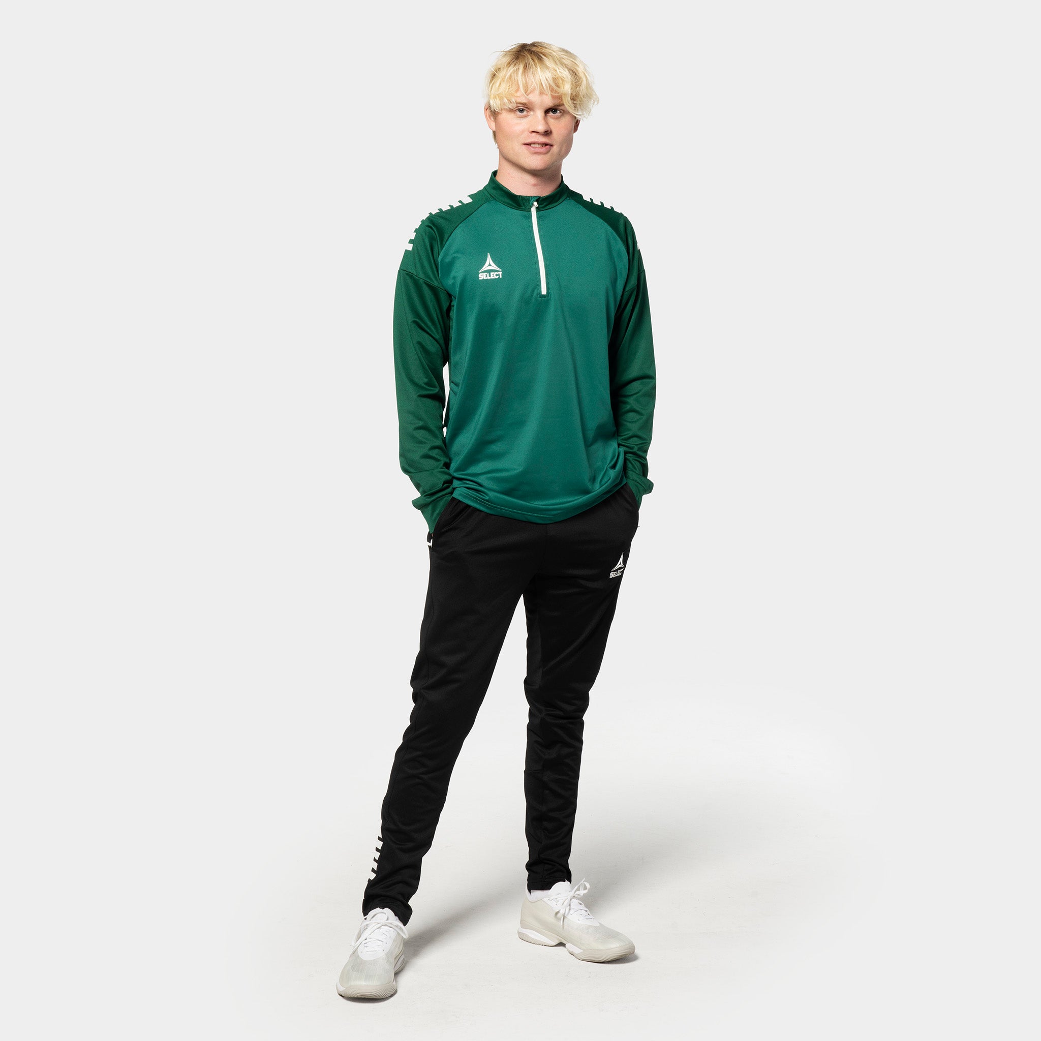 Mannlig fotballspiller i grønn/hvit Training sweat 1/2 zip Spain v25, sorte bukser, Match & Training wear.