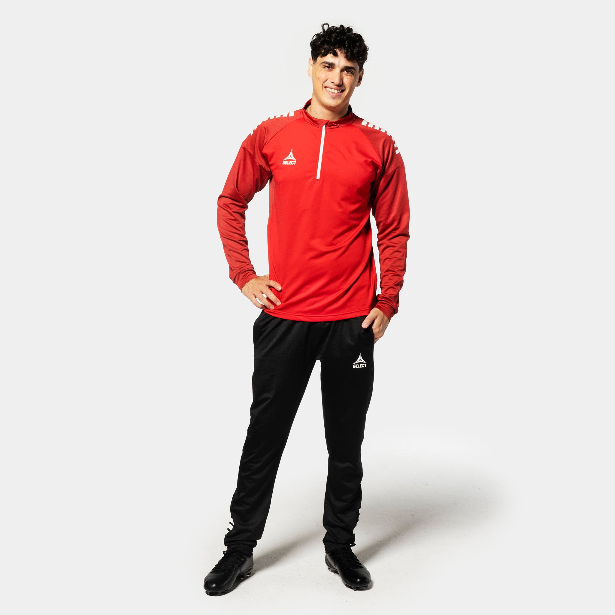 Mannlig fotballspiller i rød/hvit Training sweat 1/2 zip Spain v25, Kamp- & treningstøy, med sorte bukser, sett forfra