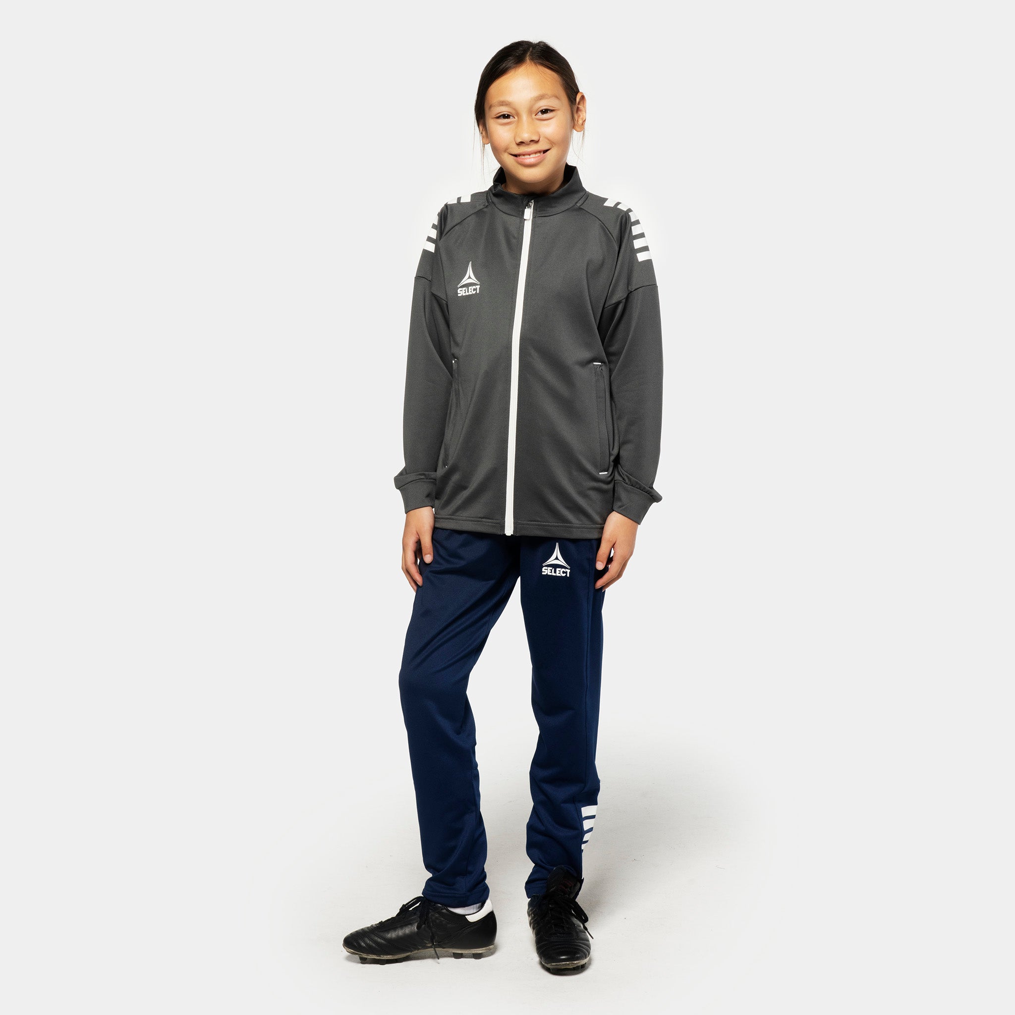 Jente fotballspiller i grå-hvit Training zip jacket og marineblå Training pants regularFit Spain v25, Match & Training wear, forfra.