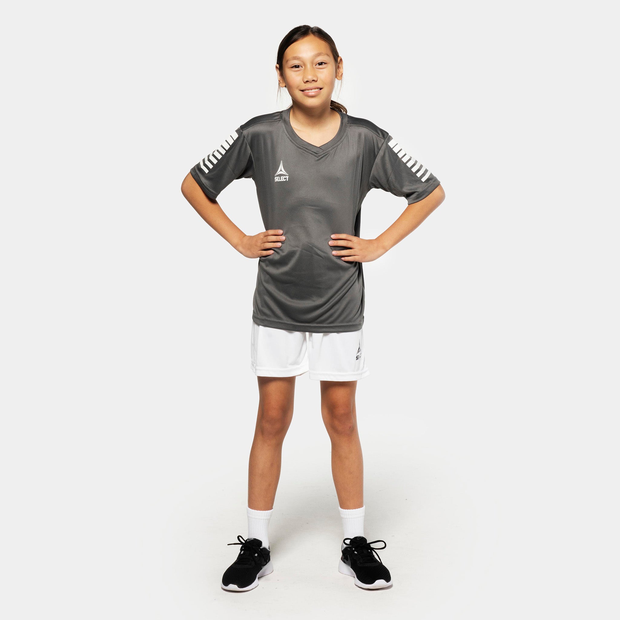 Jente fotballspiller i grå trøye og hvite Player shorts Pisa, Match & Training wear, sett forfra.