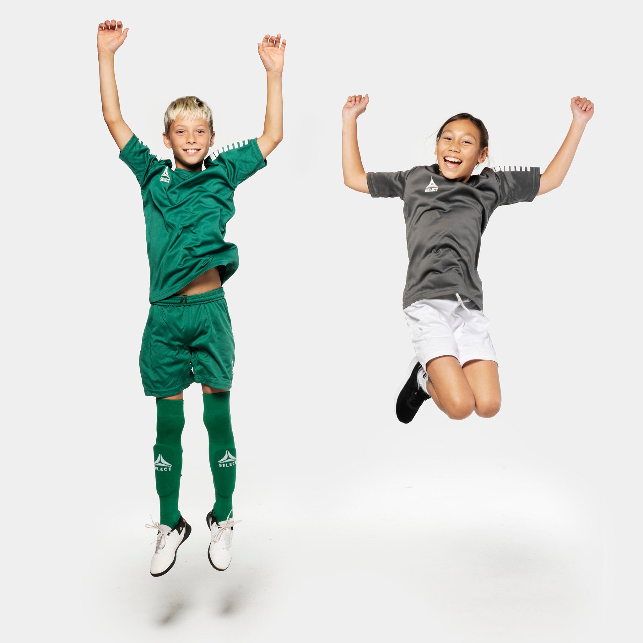 Gutt og jente fotballspillere hopper i Pisa spillershorts, Match & Training-tøy, i grønt og hvitt.