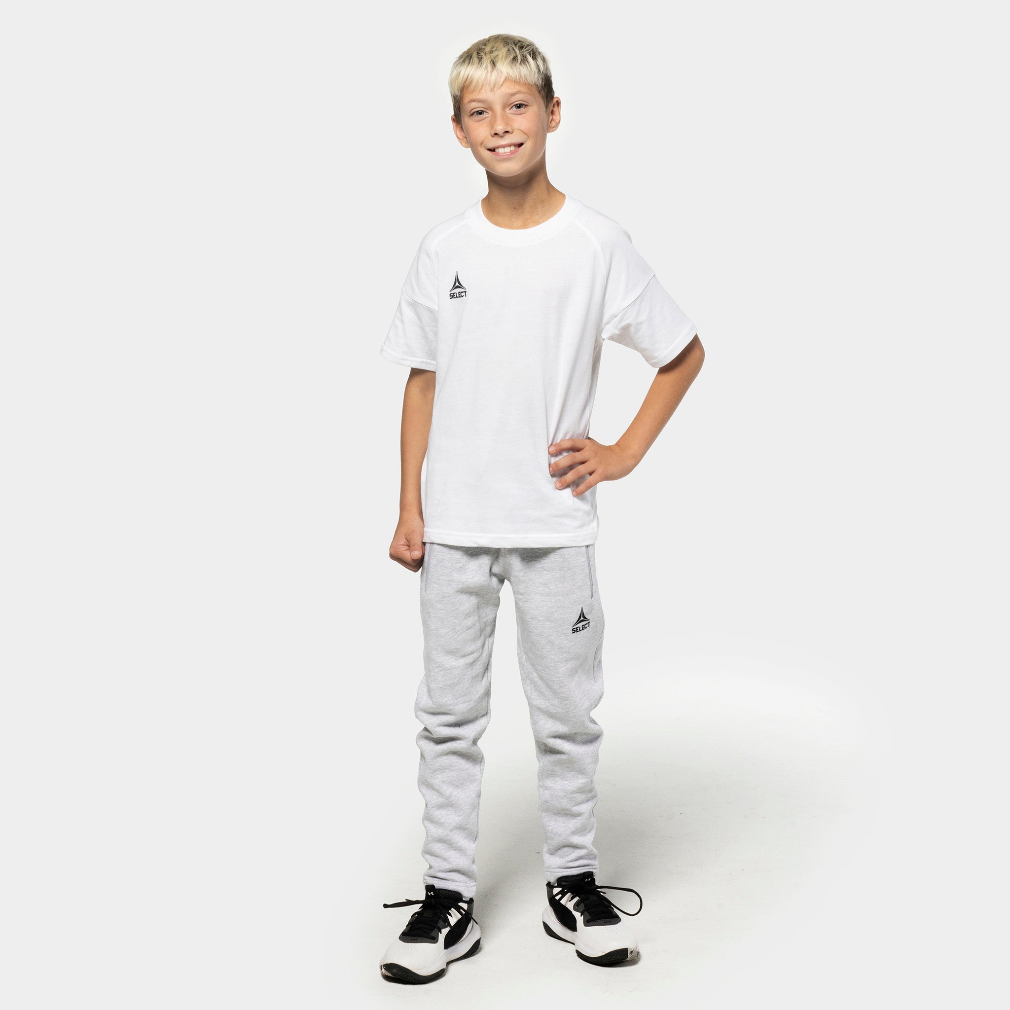 Gutt fotballspiller i hvit t-skjorte og grå Sweat pants Oxford v25, fritidsklær, sett forfra.