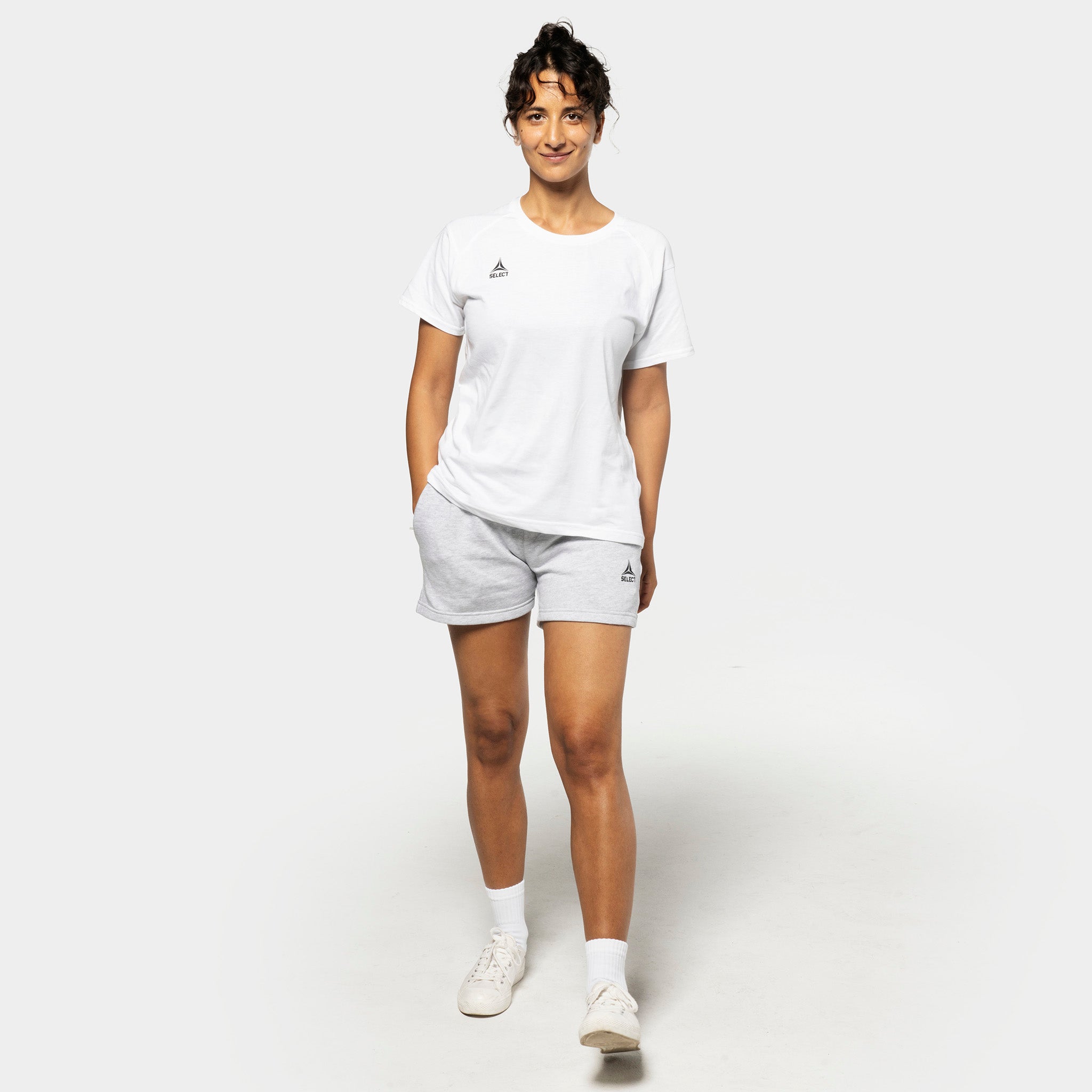 Kvinnelig fotballspiller i hvit t-skjorte og grå Sweat shorts Oxford women v25, fritidsklær, sett forfra.