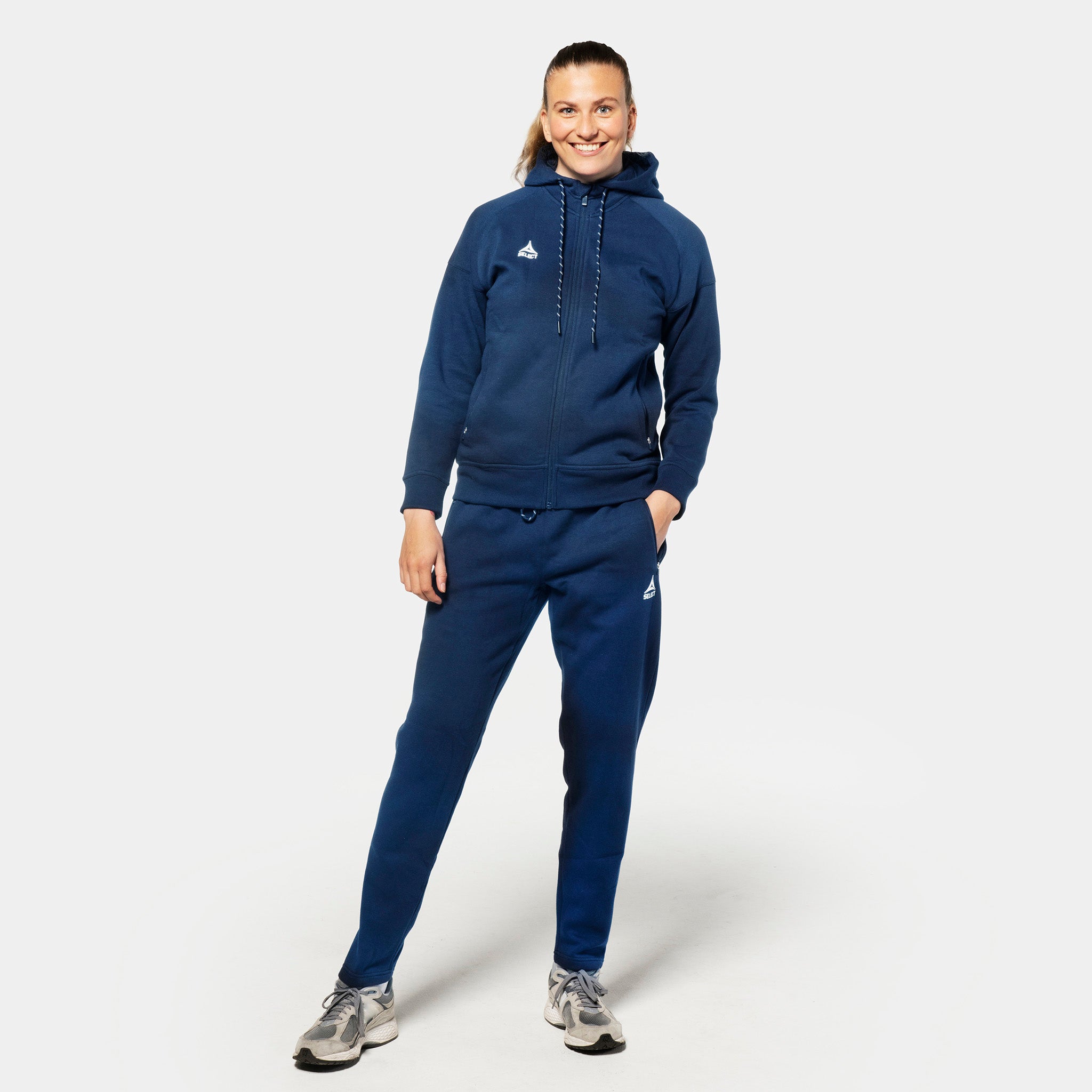 Kvinnelig fotballspiller i marineblå Sweat pants Oxford women v25 med matchende hettegenser, fritidsklær, forfra.