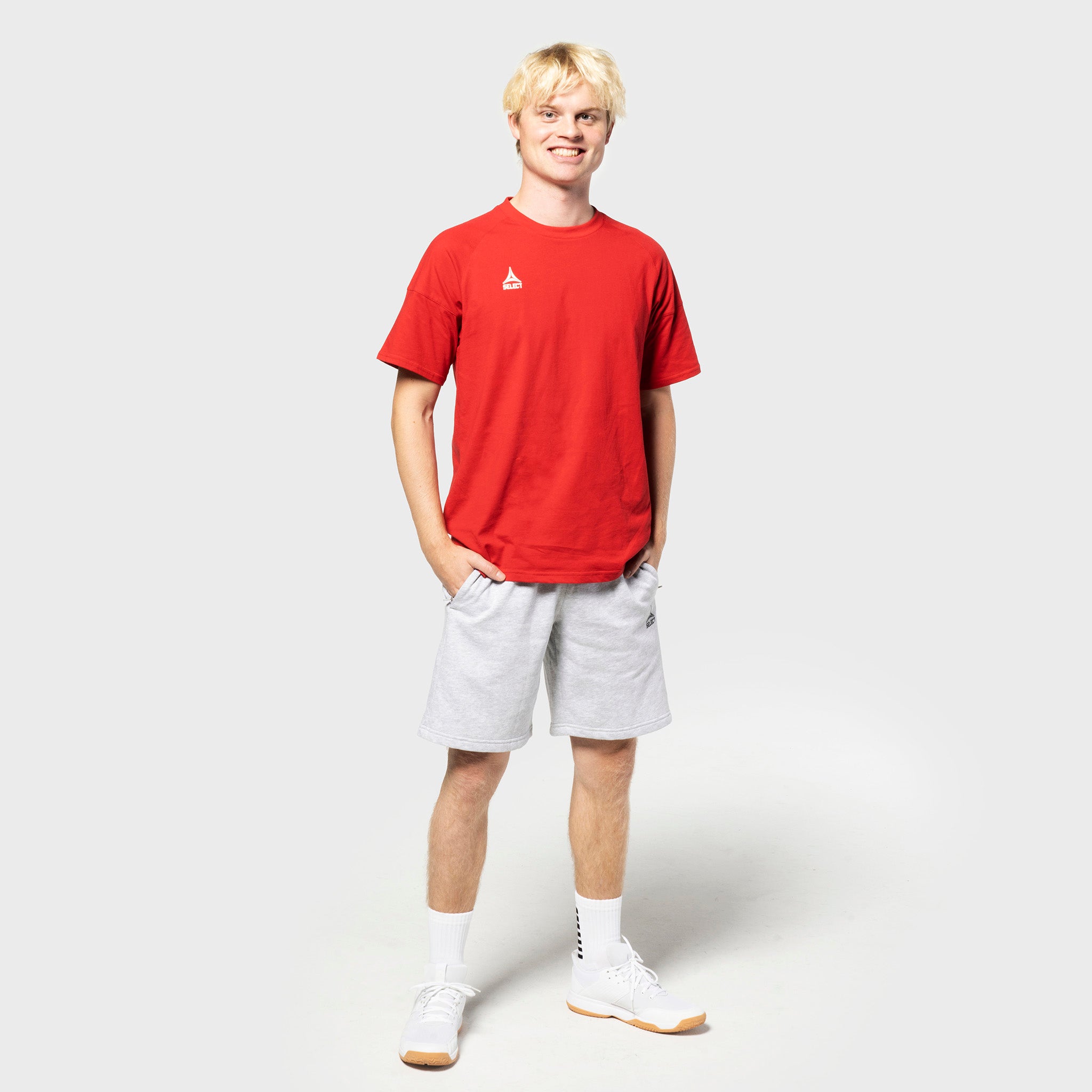 Mannlig fotballspiller i rød t-skjorte og grå Sweat shorts Oxford v25, fritidsklær, sett forfra.