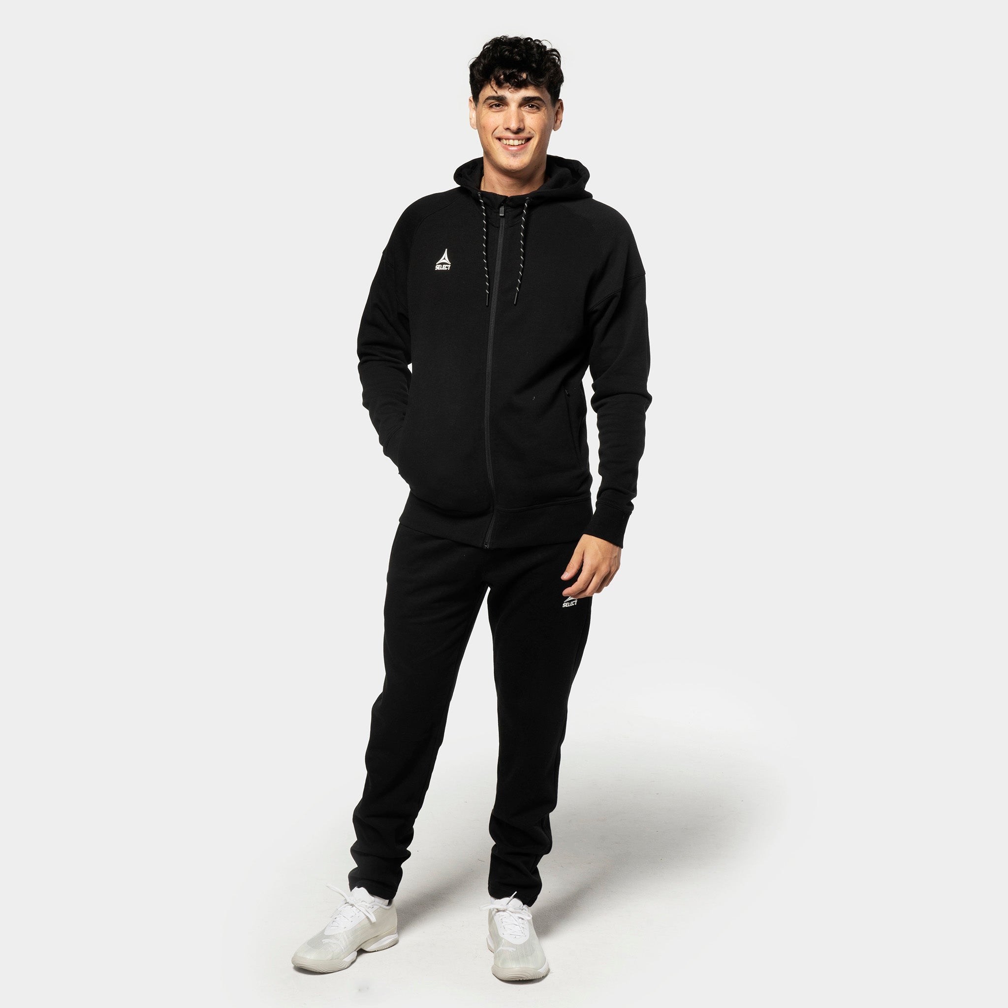 Mannlig fotballspiller i sorte Sweat pants Oxford v25 med matchende hettegenser, fritidstøy, sett forfra.