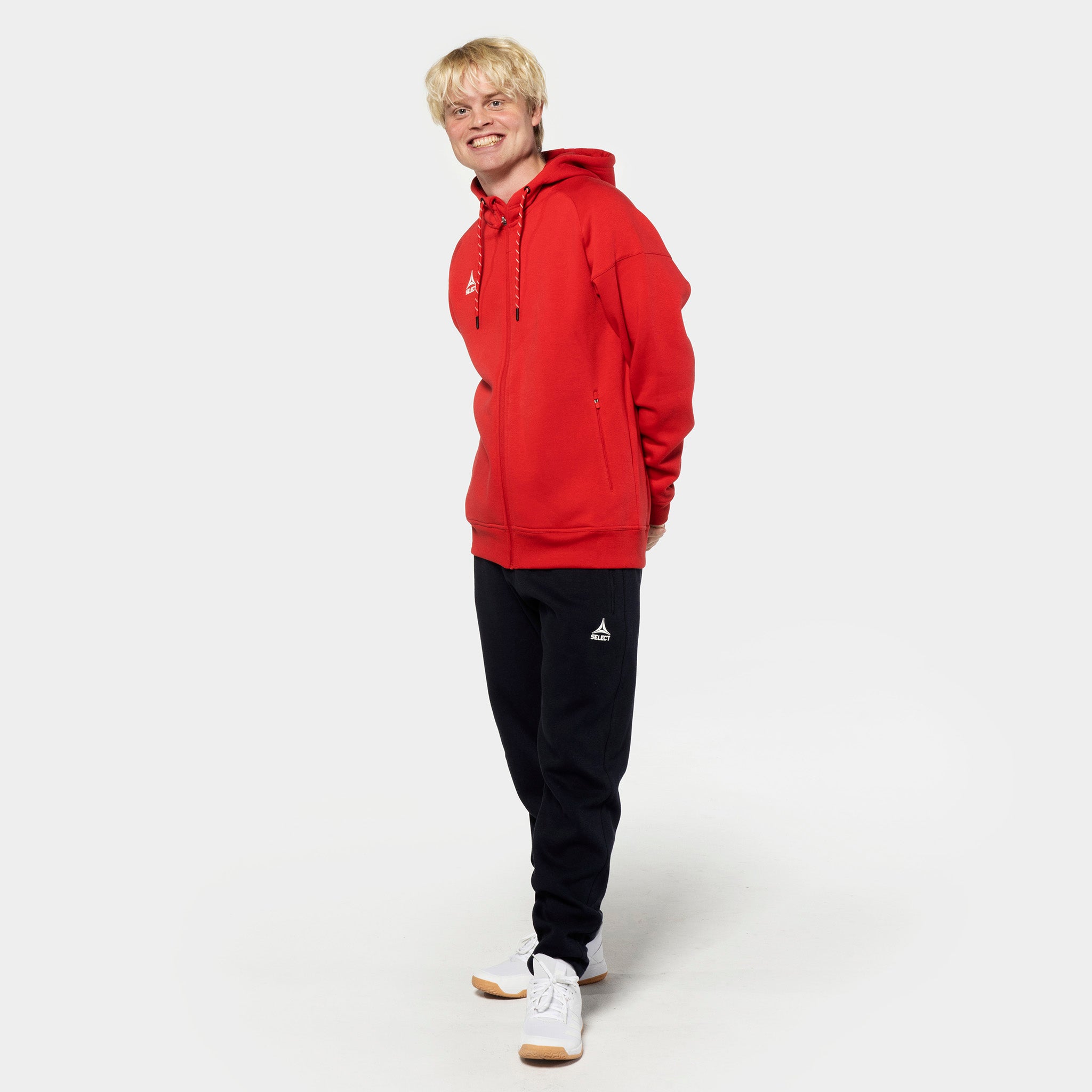 Mannlig fotballspiller i rød zip hettegenser og sorte Sweat pants Oxford v25 fritidsklær, sett forfra.