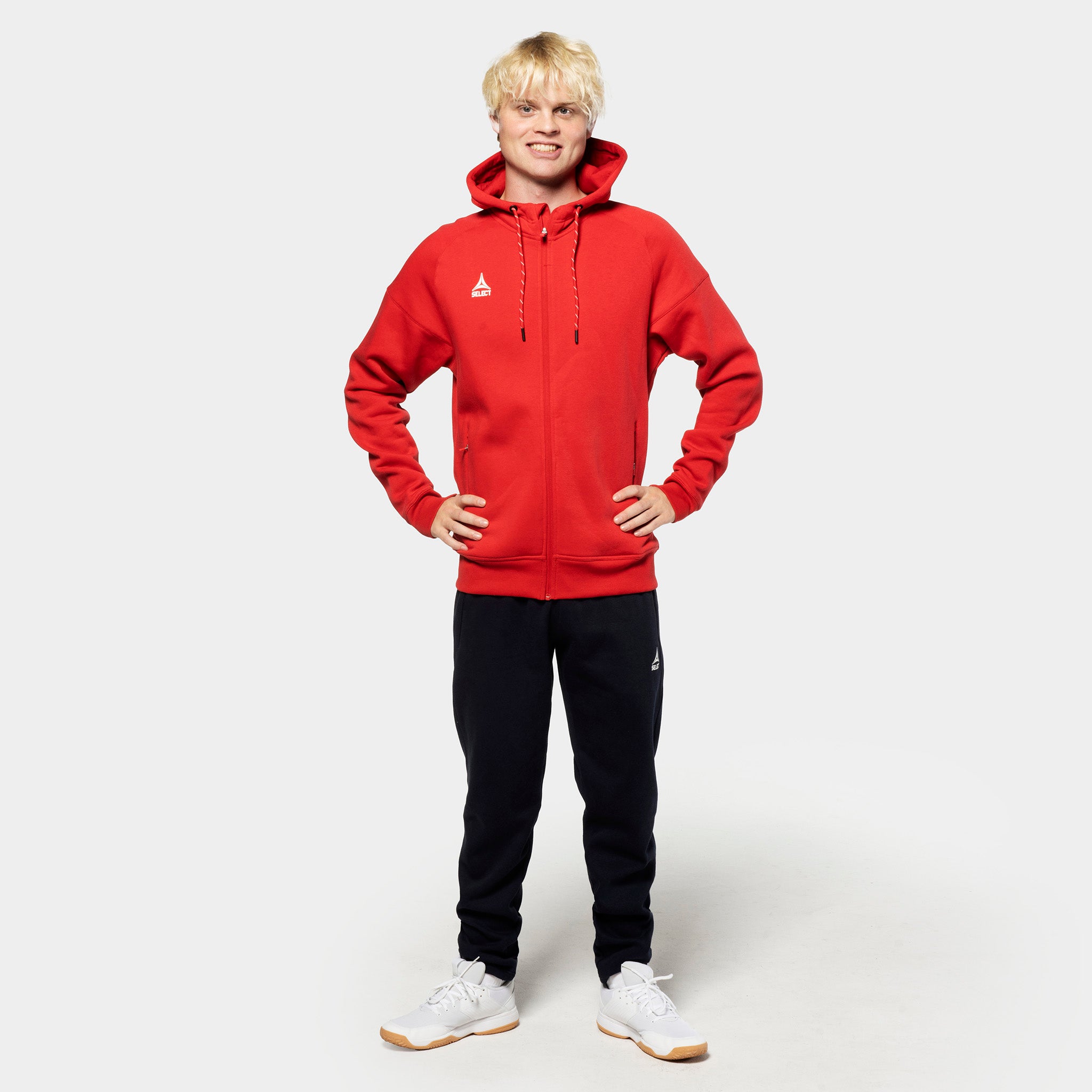 Mannlig fotballspiller i rød zip-hettegenser og svarte Sweat pants Oxford v25, fritidsklær, forfra.