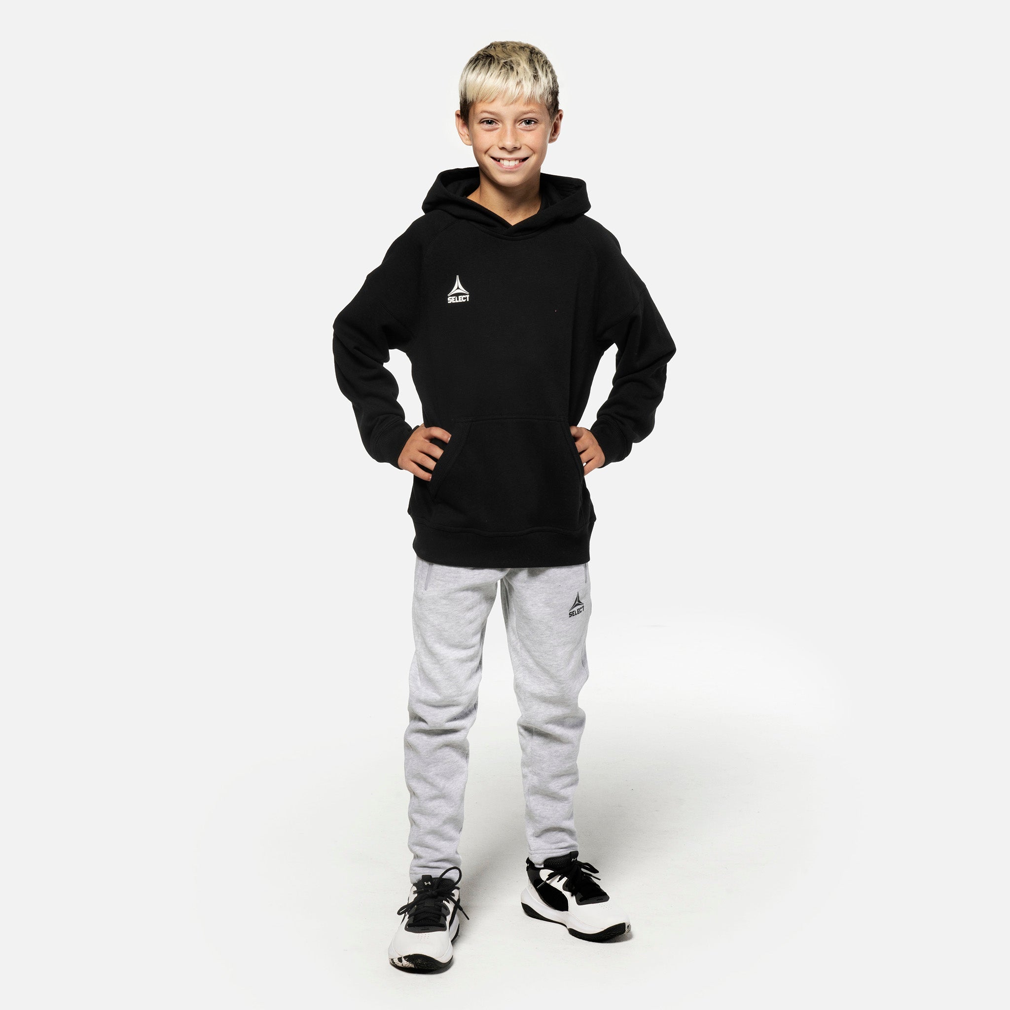 Gutt fotballspiller i grå Sweat pants Oxford v25 og sort hettegenser, fritidsklær, sett forfra.