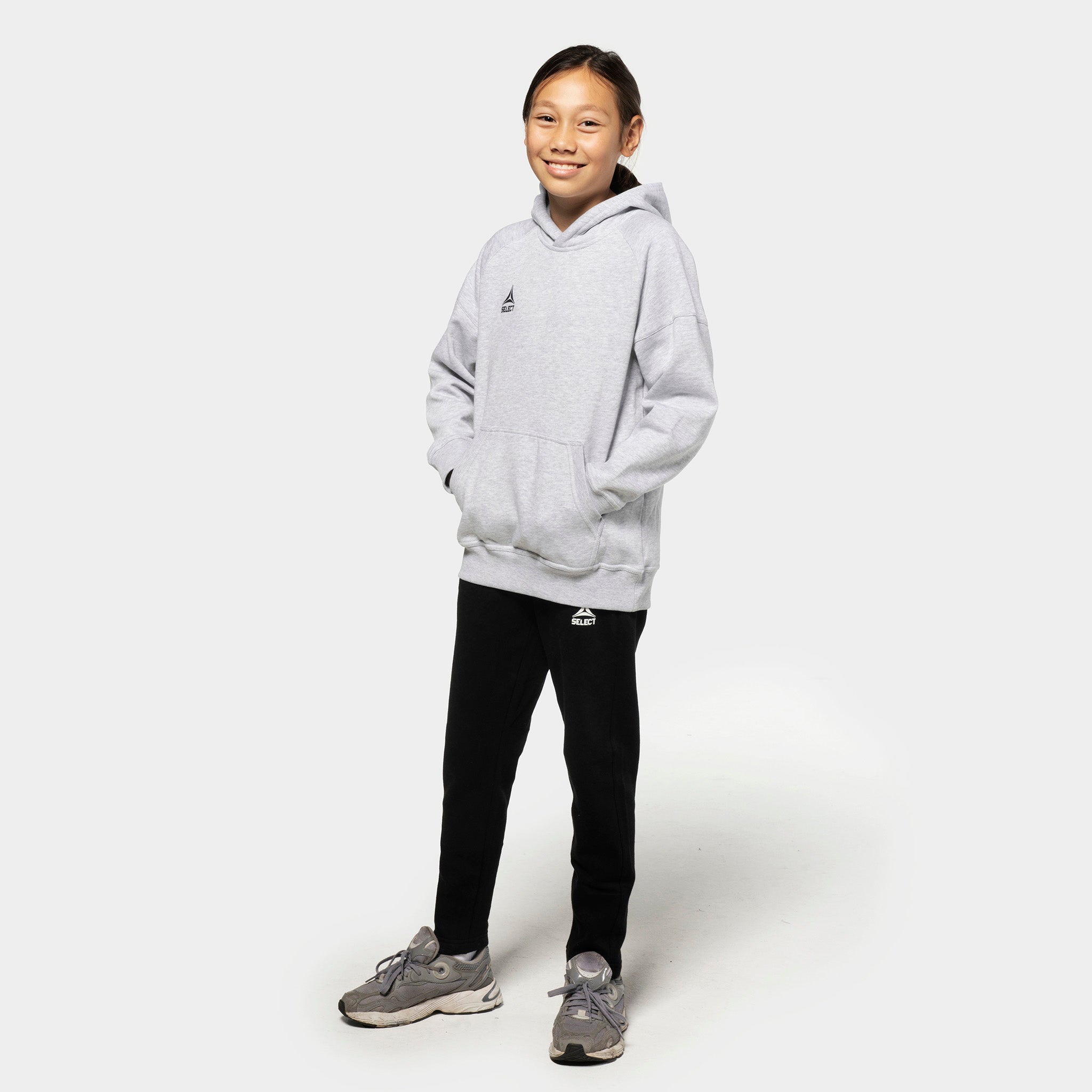 Jente fotballspiller i grå Oxford v25 hettegenser og sorte Sweat pants Oxford v25 fritidsklær, sett forfra.