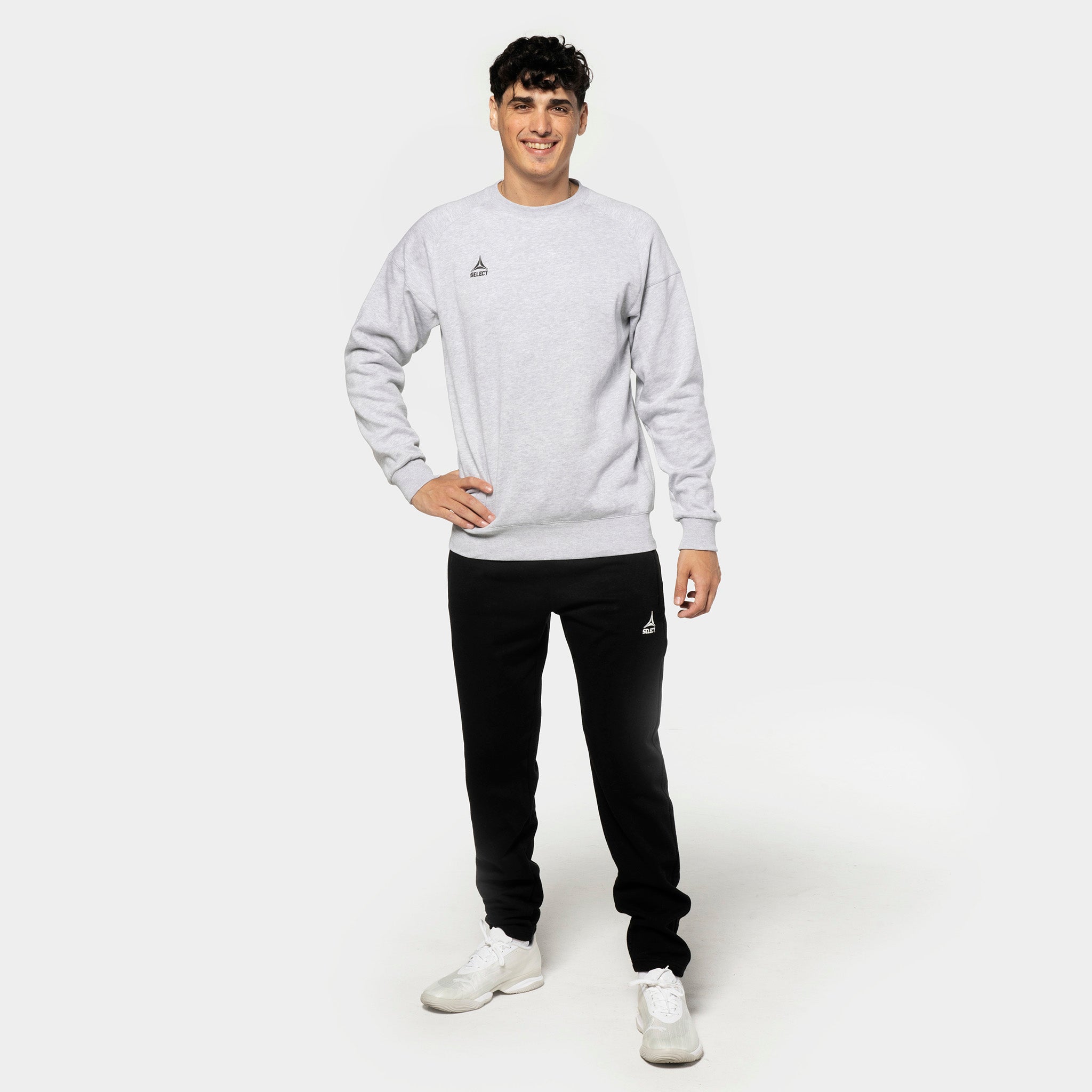 Mannlig fotballspiller i grå genser og svarte Sweat pants Oxford v25, fritidsklær, sett forfra.