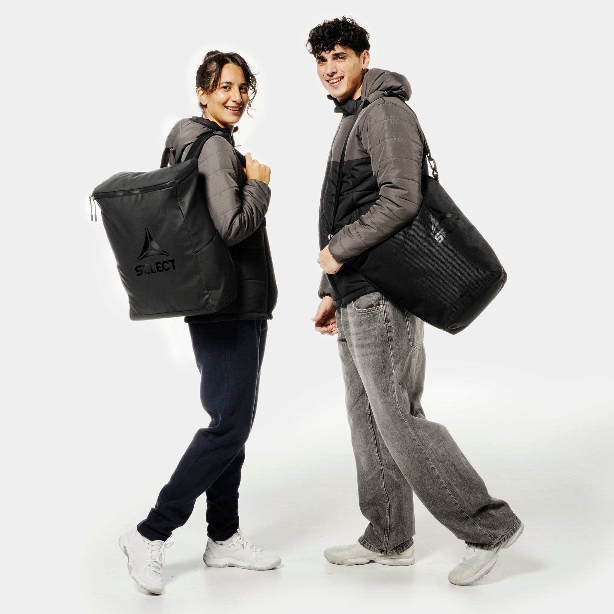 Kvinnelig og mannlig fotballspiller med sorte Crossbody v25 sportsbager med hvit logo.